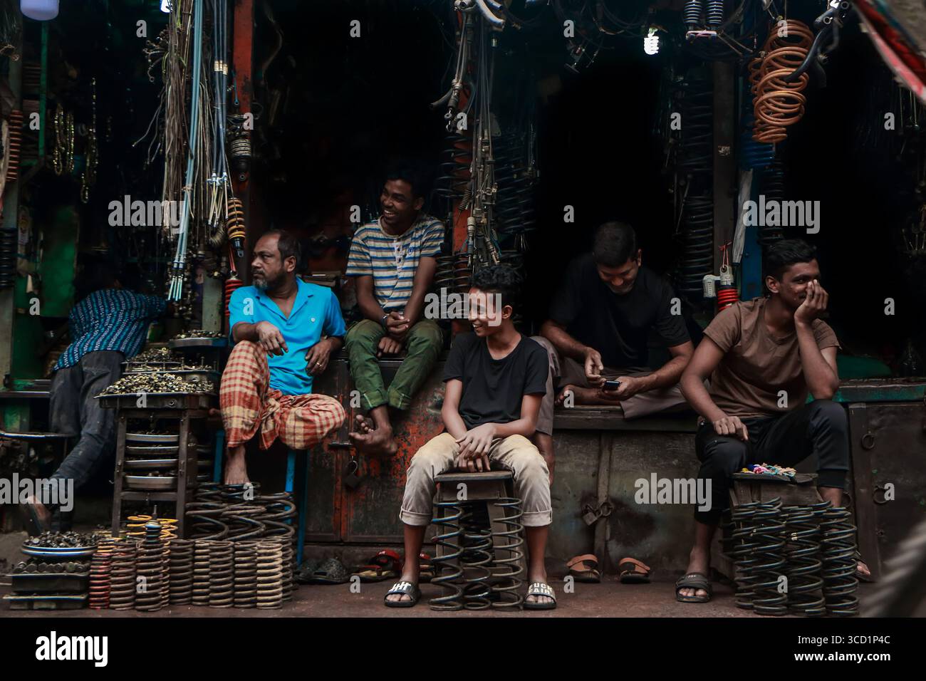 Dhaka, Bangladesch - 09. November 2019: Blick auf Männer auf dem schwach beleuchteten Dhaka-Metallmarkt, umgeben von einem Labyrinth aus hängenden Drähten und Metallteilen. Stockfoto