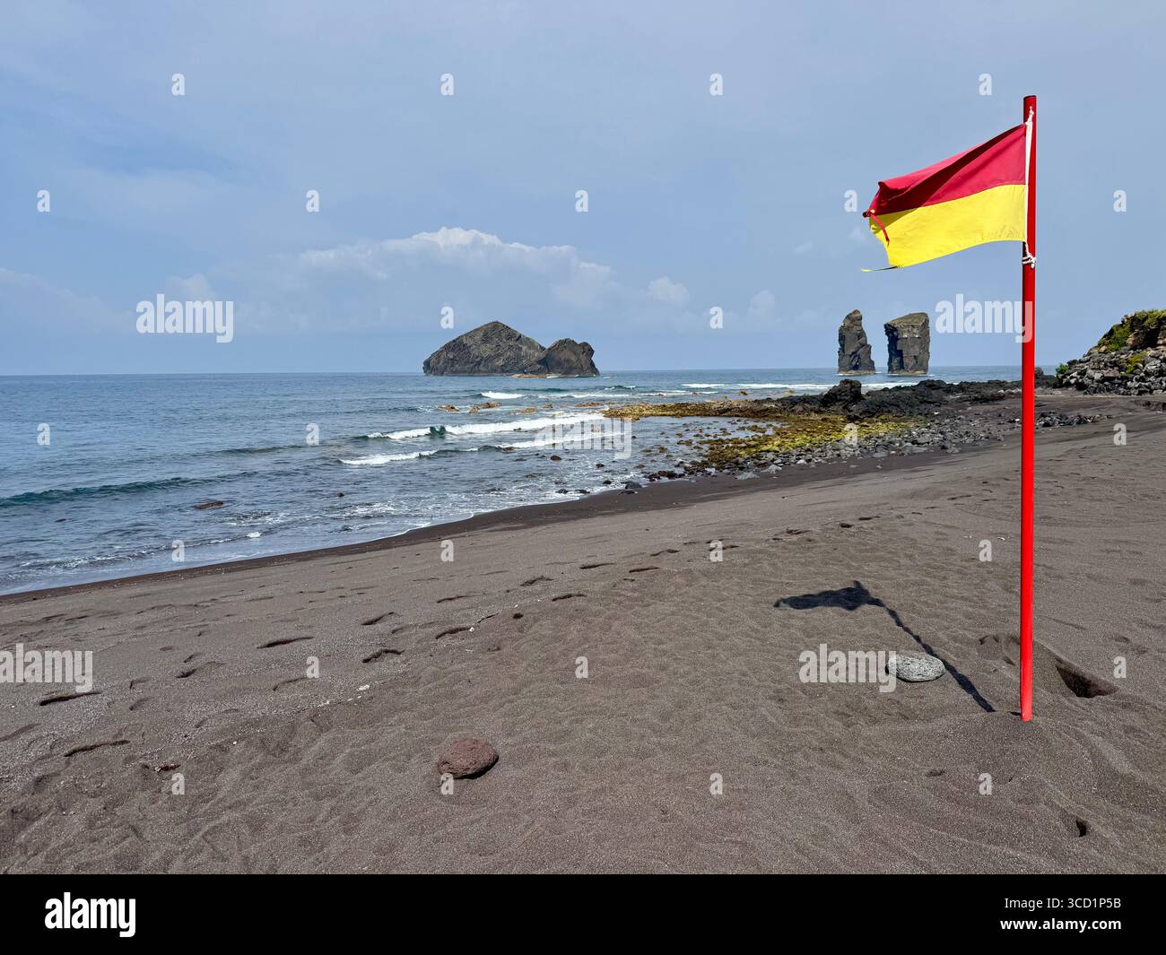 Rote und gelbe Rettungsfahne, die einen überwachten Badebereich am Strand von Mosteiros auf den Azoren, Portugal, anzeigt. Stockfoto