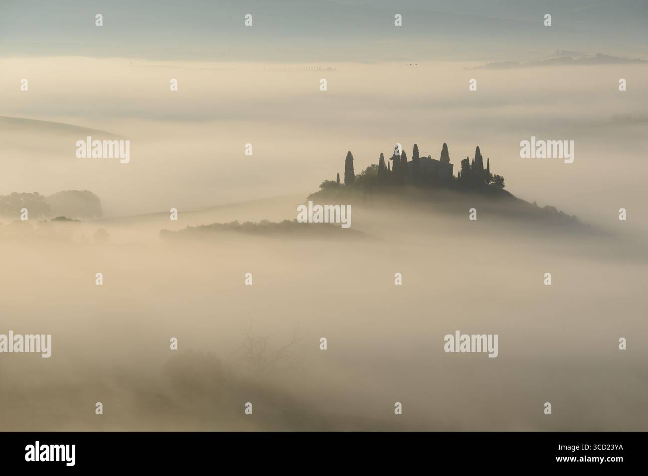 Blick auf eine toskanische Villa auf einem Hügel, umgeben von einem Meer aus ätherischem Nebel, die eine traumhafte Landschaft schafft, San Quirico d'Orcia, Toskana, Italien. Stockfoto