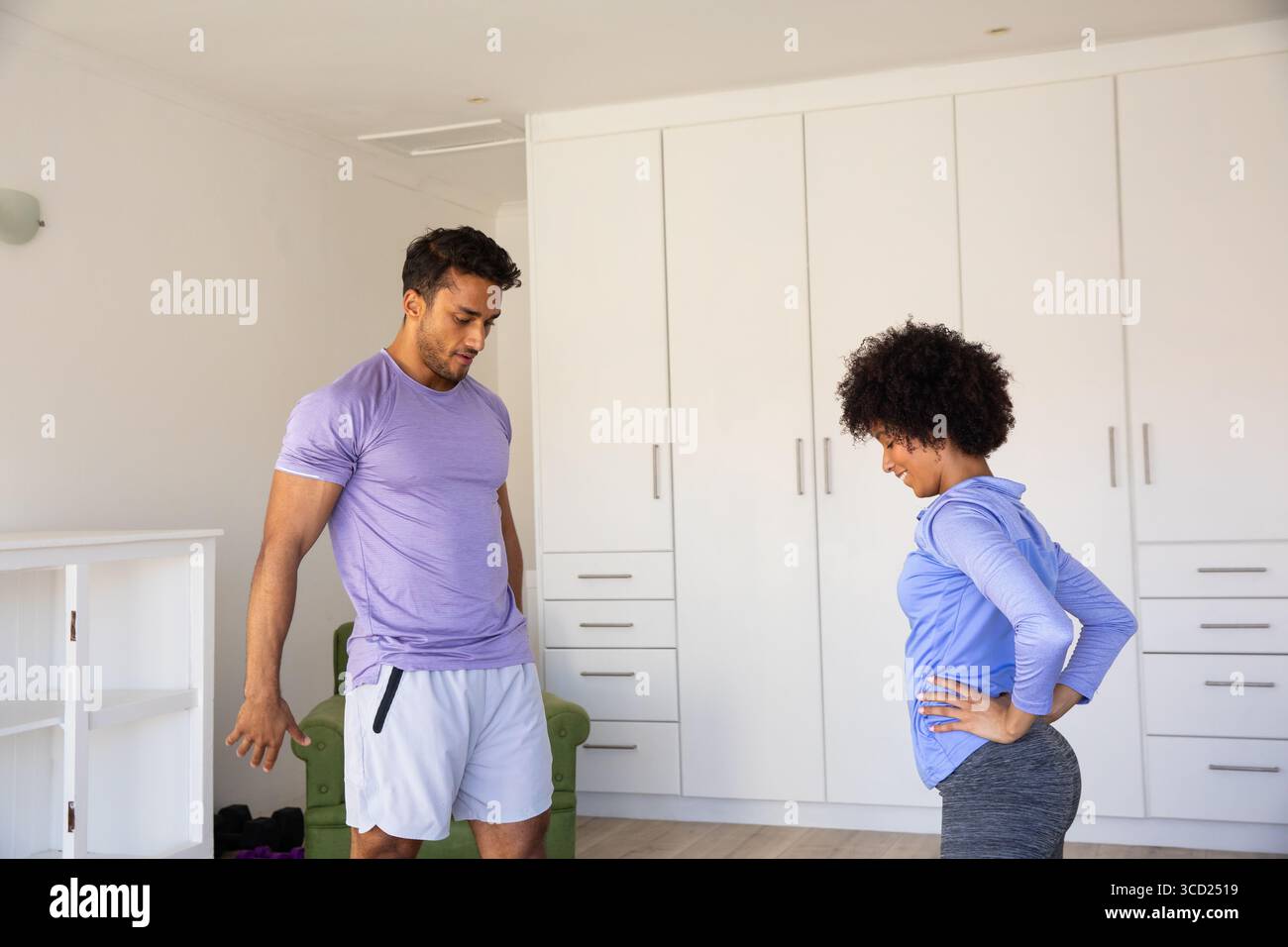 Verschiedene männliche Freunde, die ihre Beine auf Holzboden in einem Heimtrainingsbereich von Kleiderschränken strecken Stockfoto