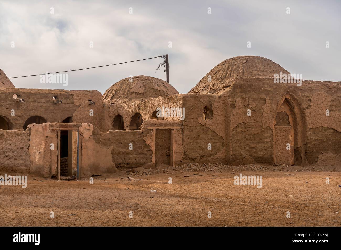 Alte Moschee mit Kuppeldächern und Bogenfenstern steht in Fderik, Mauretanien, eingerahmt von Sahara-Bergen und leerer Asphaltstraße in abgelegener Wüstenstadt. Stockfoto