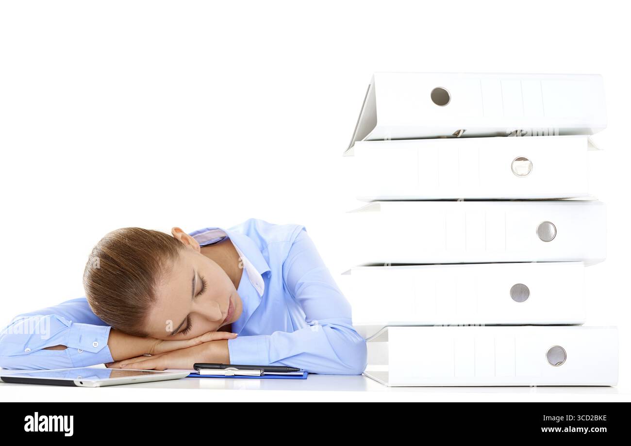 Müde Geschäftsfrau, die von Überarbeit erschöpft war, schlief an ihrem Schreibtisch neben einem hohen Stapel von Büromappen Stockfoto
