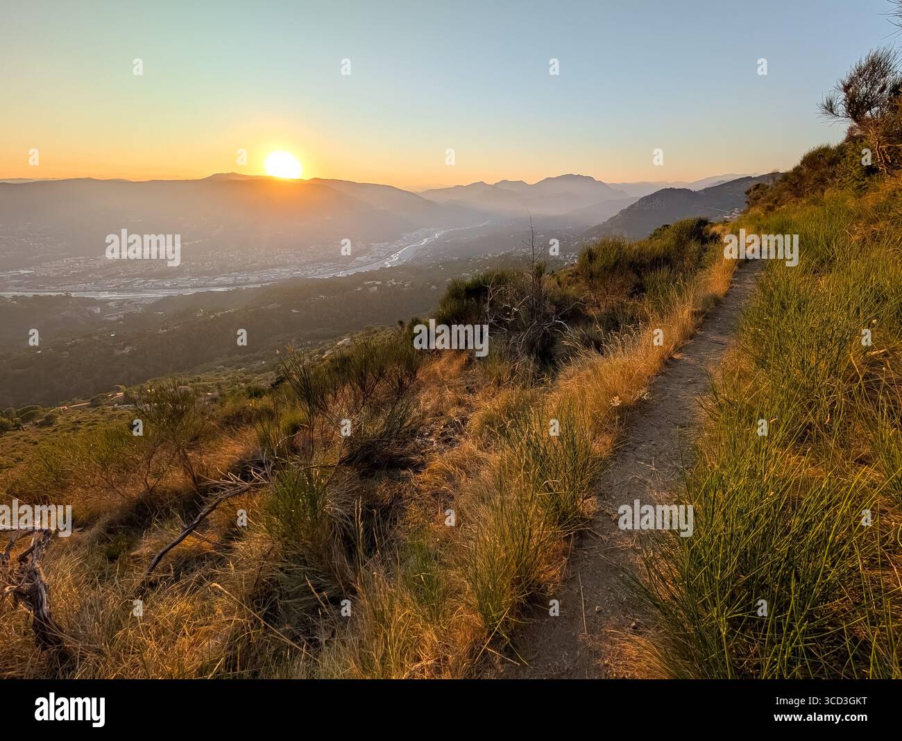Wunderschöner Sonnenuntergang über dem Var-Tal und den Bergen von einem Wanderweg in den Hügeln oberhalb von Nizza, der französischen Riviera. Stockfoto