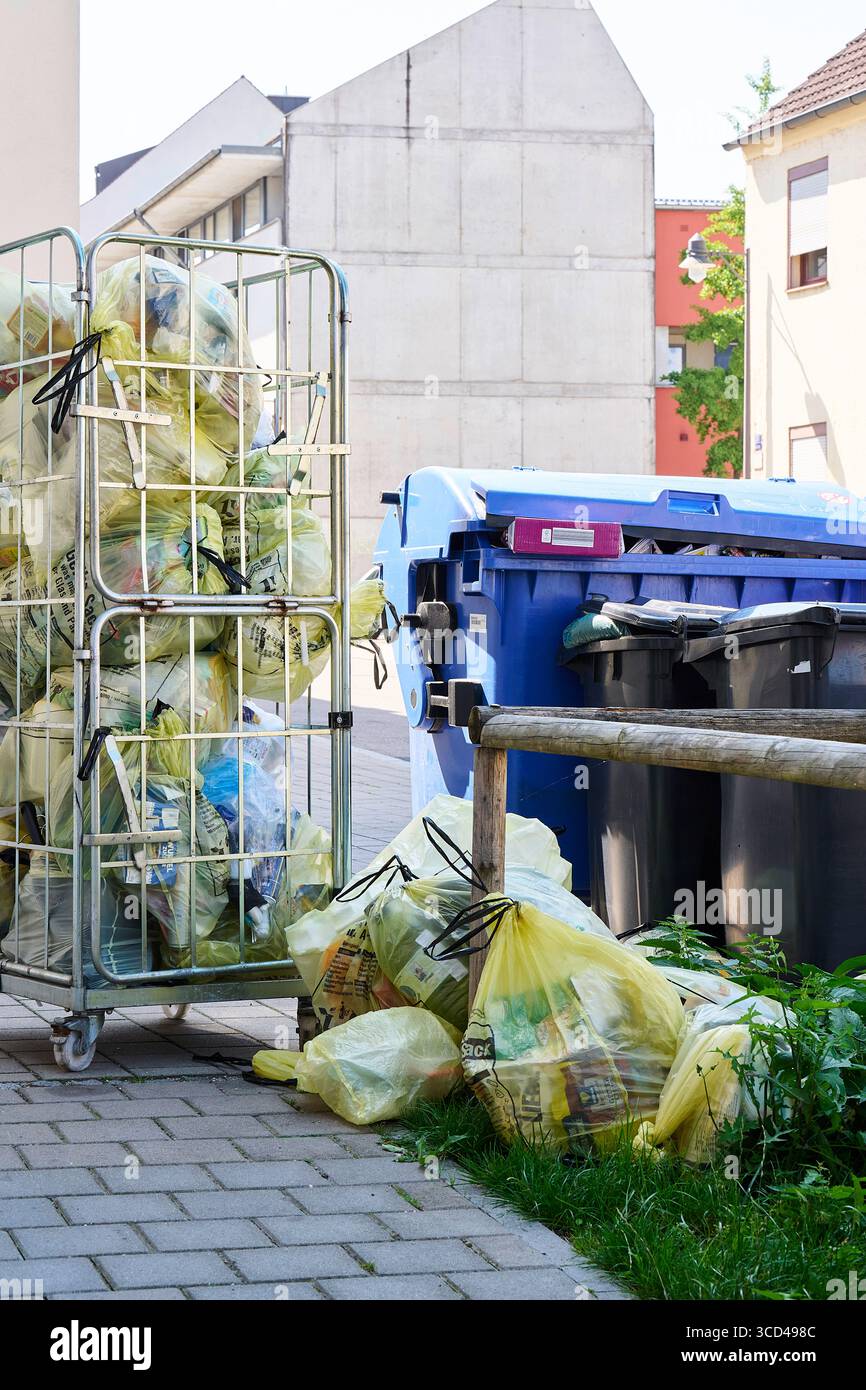 Gelbe Säcke und Mülltonnen warten am Straßenrand auf Abholung Stockfoto
