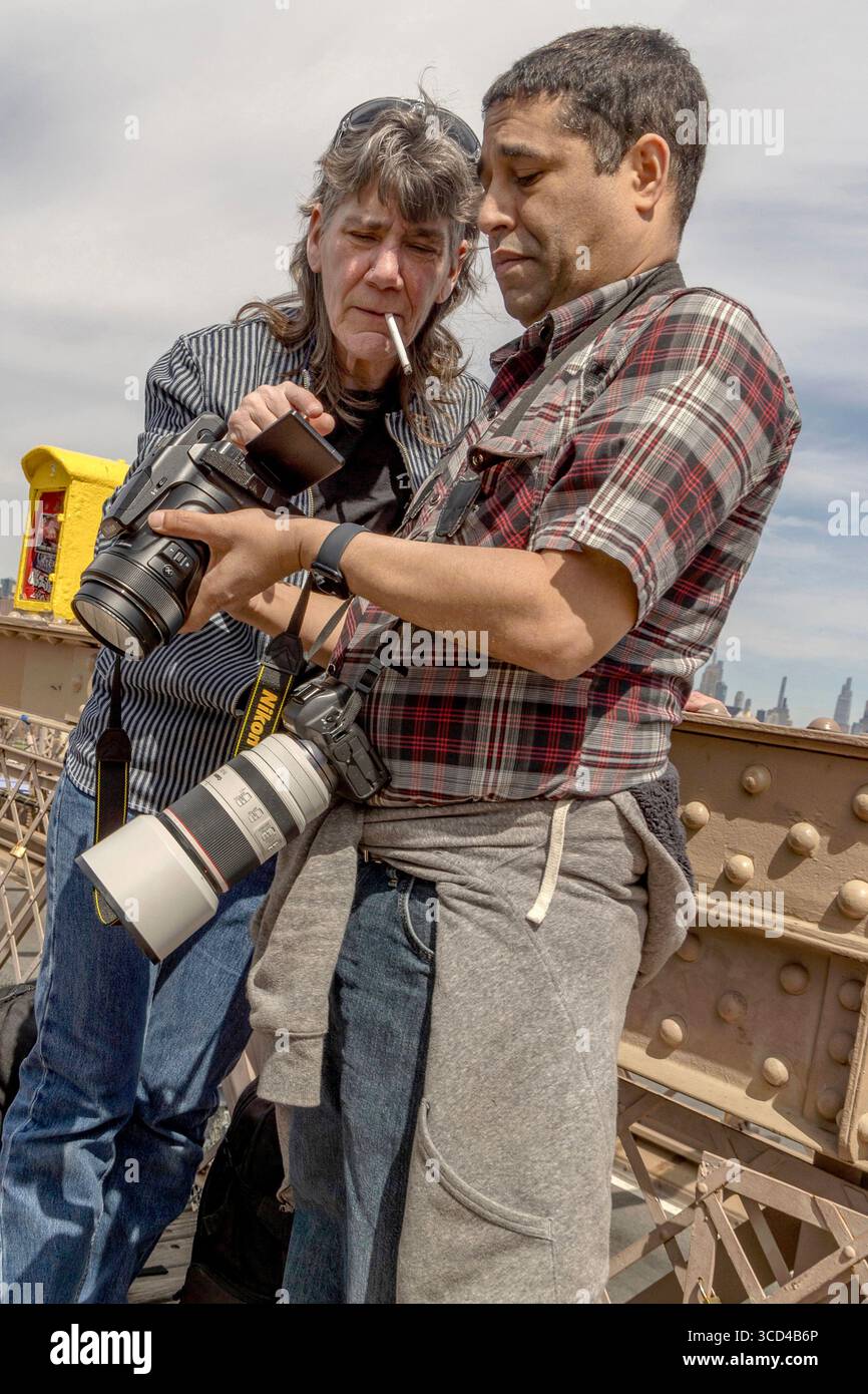 Nahaufnahme von zwei Fotografen, die Fotos auf Brooklyn Bridge, Manhattan, New York, USA, ansehen, um urbane Fotografie und das Straßenleben festzuhalten. Stockfoto