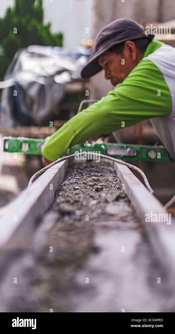 Eine Wasserwaage liegt auf Beton auf, um eine gleichmäßige Oberfläche zu gewährleisten, ein wesentlicher Schritt zur Aufrechterhaltung von Präzision und Qualität bei Bauarbeiten Stockfoto