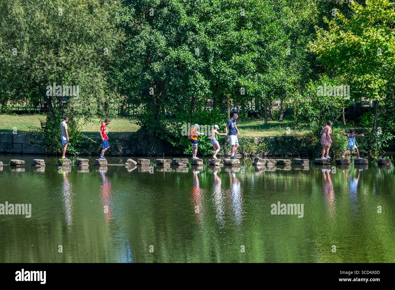 Chaves, Portugal: 13. August 2023: Mann mit Kindern spazieren entlang des tamega River Park, einem touristischen öffentlichen Park im historischen Zentrum Stockfoto