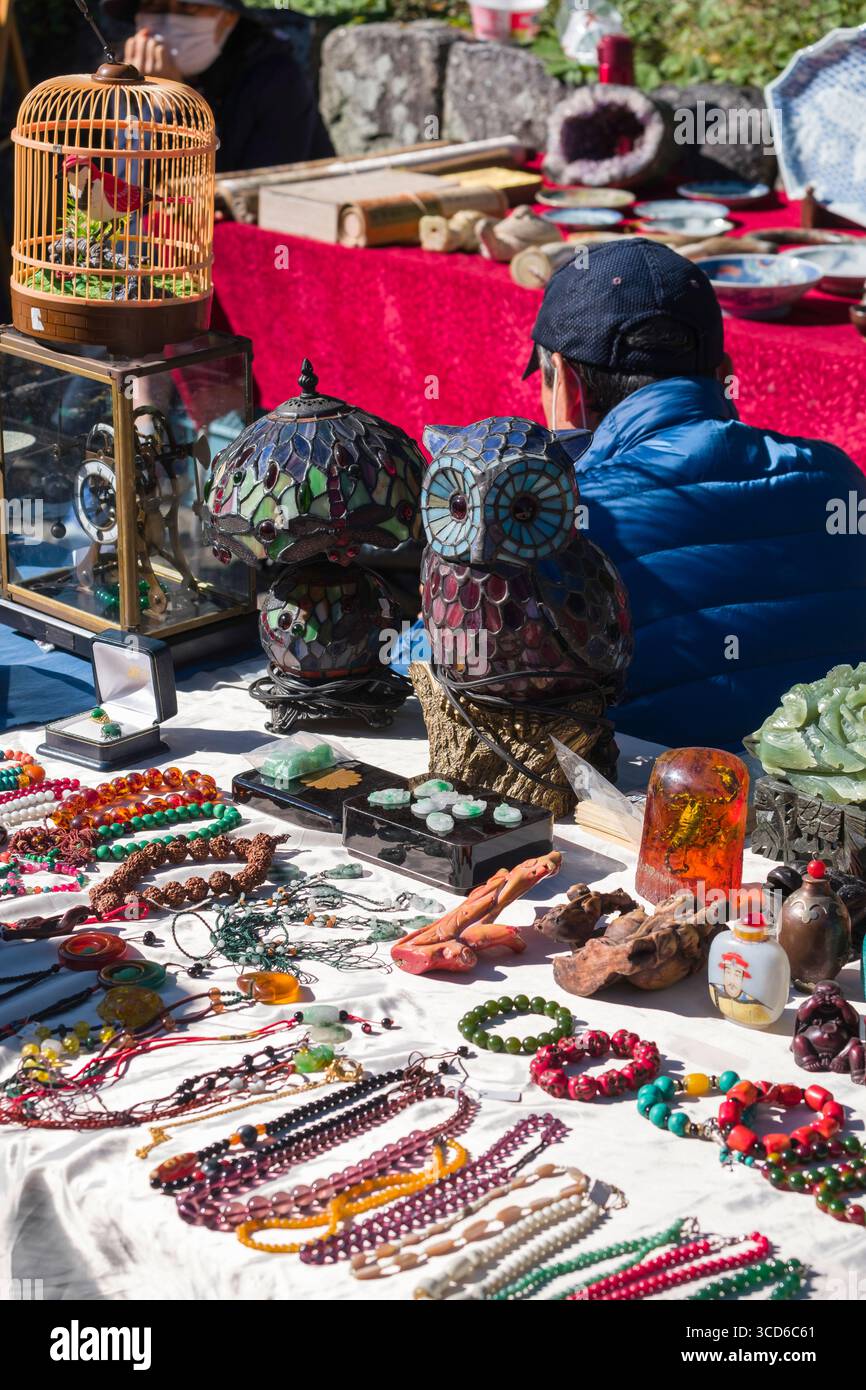 Männlicher Verkäufer, der Schmuck und verschiedene Kleinteile während des monatlichen Flohmarktes am Tenmangu-Schrein, Bakurocho, Kamigyo Ward, Kyoto, Kansai, verkauft. Honshu, Stockfoto