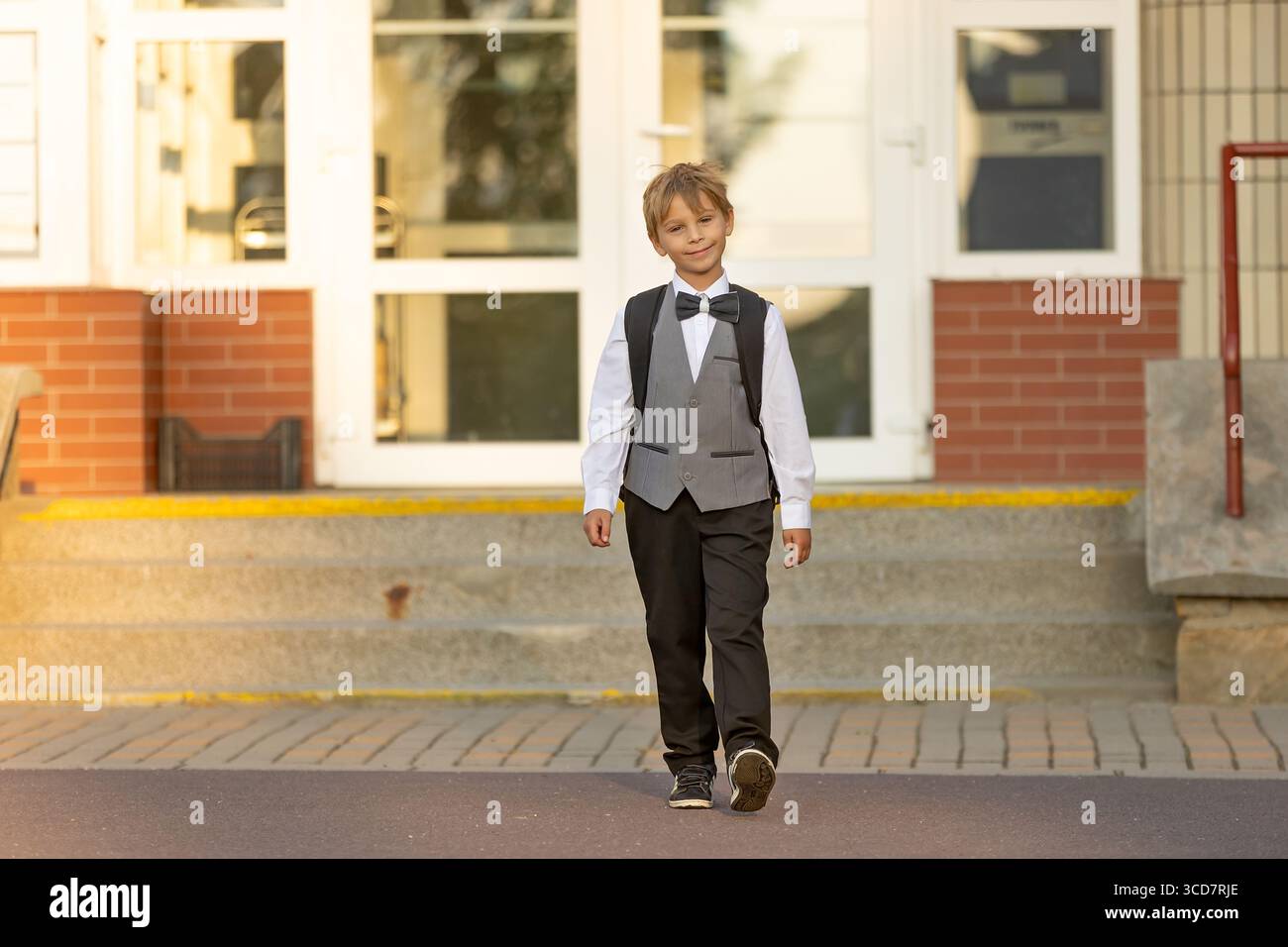 Süßes Schulkind der ersten Klasse, das zur Schule geht. Erster Schultag für einen Erstklässler, Kind beginnt die Schule, bringt Blumen für den Lehrer, Carin Stockfoto