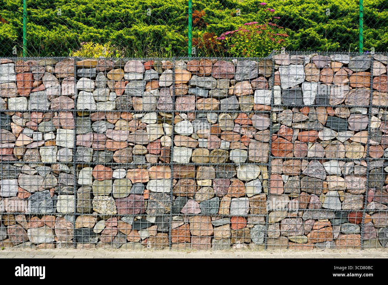 Nahaufnahme einer Gabionenwand aus bunten Natursteinen in einem Drahtgeflecht, die zur Landschaftsgestaltung und Erosionskontrolle verwendet wird Stockfoto