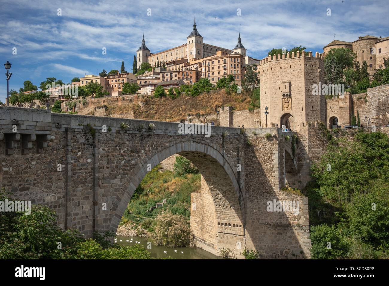 Sonniger Blick auf die Puente de Alcántara und die Alcázar von Toledo in Spanien. UNESCO-Steinbefestigung auf Hill. Kulturerbe in Europa. Stockfoto