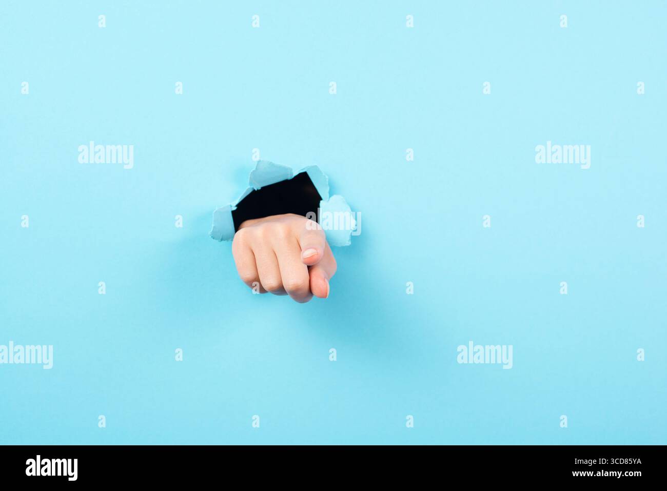 Finger Zeigt Nach Vorne, Kopierraum Für Werbung Und Marketing, Aufmerksamkeitsgeste, Loch In Blauem Papier Stockfoto