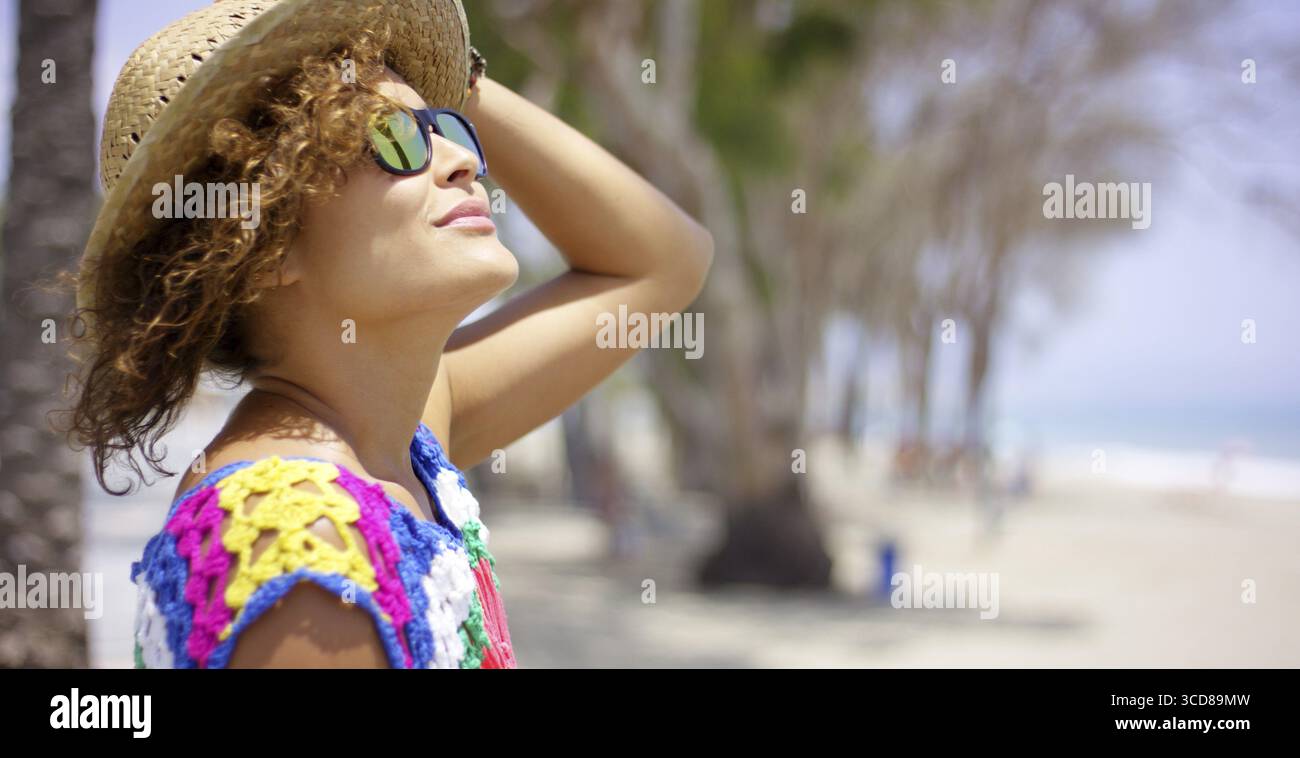 Ziemlich erwachsenes Weibchen in reflektierende gelbe Sonnenbrille und Strohhut außerhalb am Strand auf der Suche nach oben mit Textfreiraum Stockfoto
