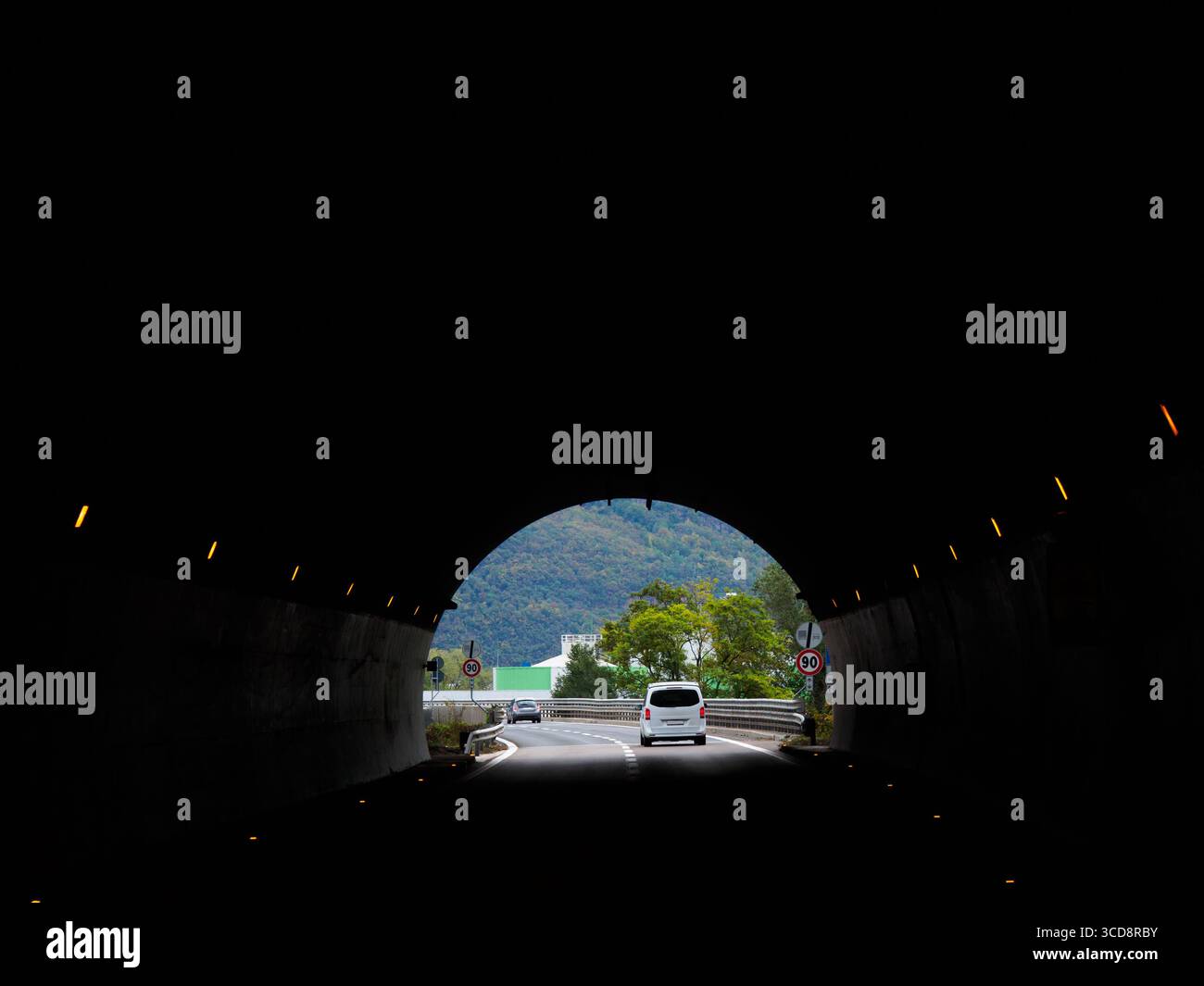 Halber Kreis am Ende des Tunnels. Auto, das durch den Tunnel fährt, sieht man deutlich die Vorderansicht. Leichter Verkehr im ländlichen Italien, auf dem Weg nach Dolomite. Stockfoto