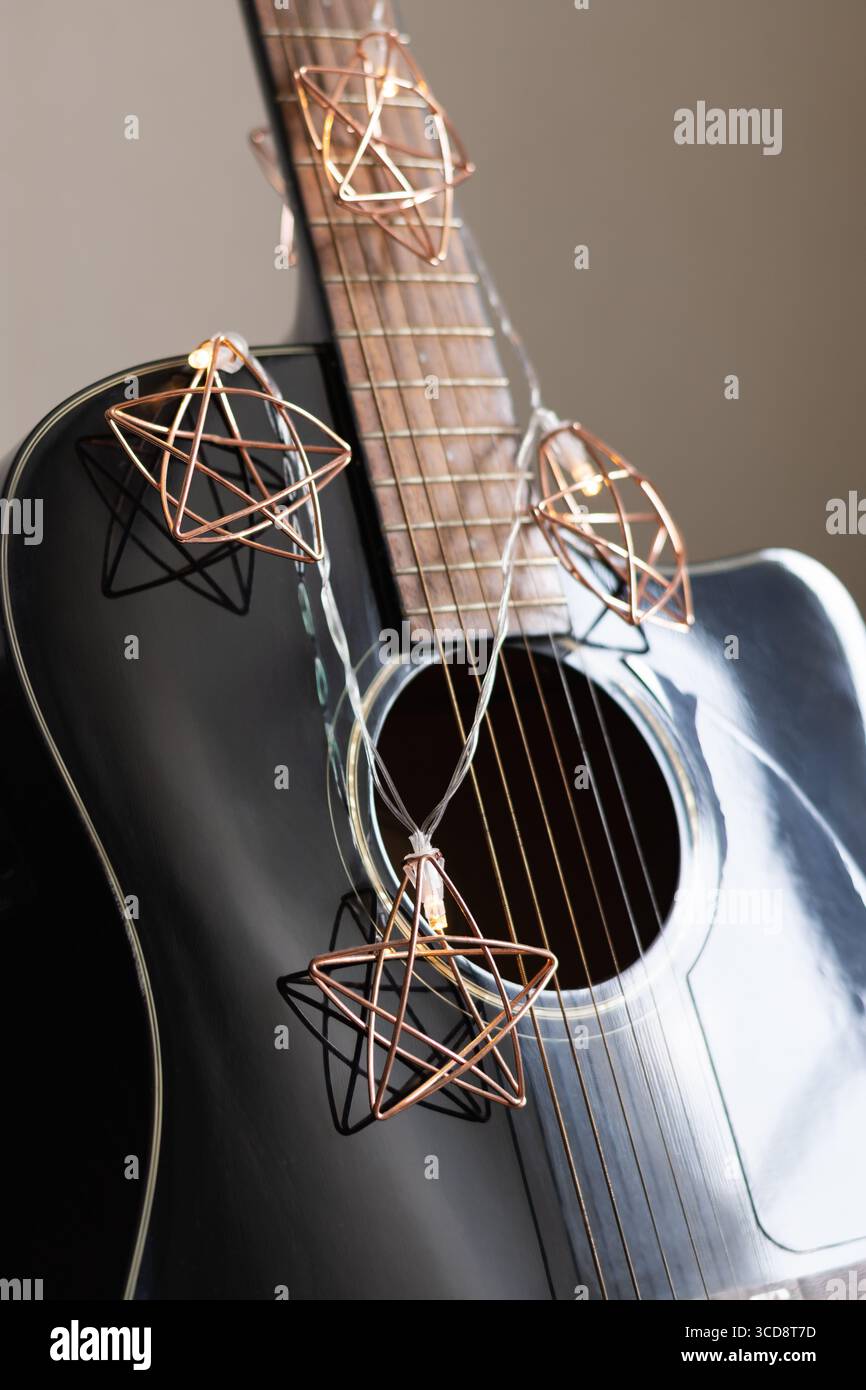 Akustikgitarre verzierte Weihnachtsgirlande als Sterne. Weihnachtslieder. Musikinstrument. Vertikal. Nahaufnahme. Stockfoto