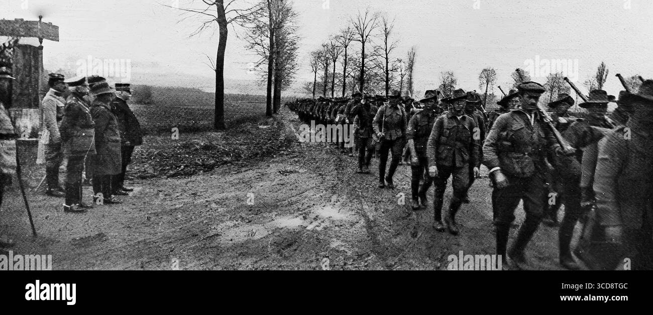April 1916 L’Illustration Foto von britischen Truppen, die während des Ersten Weltkriegs an einem Landkreuz in Frankreich vormarschierten und vor General Joseph Joffre vorbeifuhren. Die Soldaten marschierten in voller Reihenfolge mit Gewehren auf einer von Bäumen gesäumten Straße vor. Dieser Moment veranschaulicht die Koordination französischer und britischer Truppen an der Westfront, wobei hohe Kommandos die Truppenbewegungen nahe der Front beobachten. Stockfoto