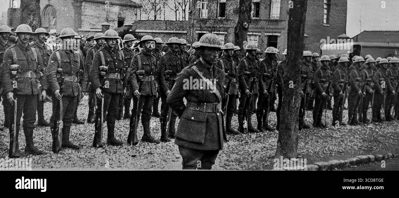 April 1916 L’Illustration Foto von neu angekommenen britischen Truppen im besetzten Frankreich während des Ersten Weltkriegs mit dem kürzlich eingeführten Stahlhelm. Soldaten stehen in Formation auf einem Dorfplatz, die die sich entwickelnde Ausrüstung und Organisation der britischen Armee widerspiegeln. Dieses Bild zeigt die Anpassung an die moderne Kriegsführung und die Stärkung der Westfront durch neue Truppen. Stockfoto