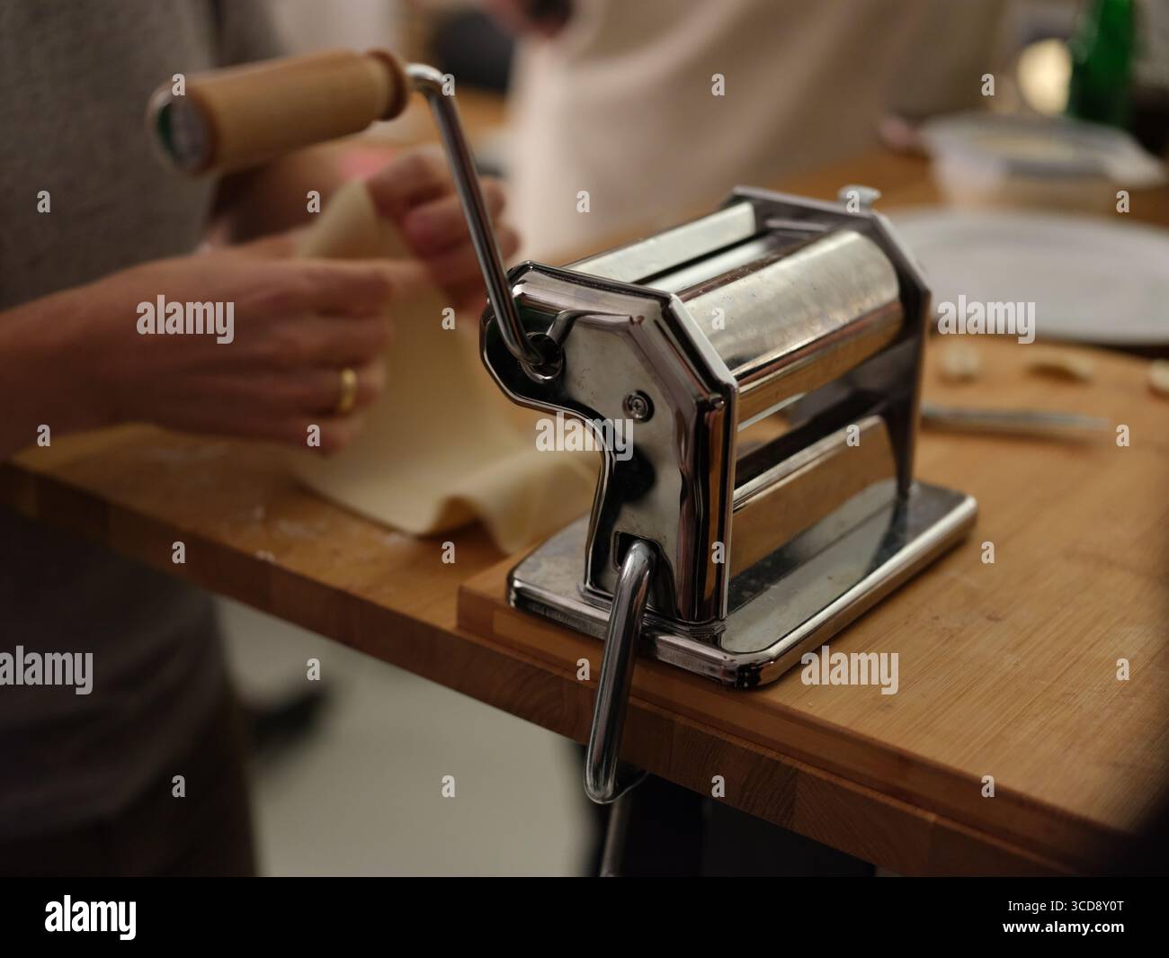 Gruppe von Menschen, die frischen Teig von Hand in der Küche zubereiten, Nahaufnahme des Kochprozesses, kulinarische Kunst und traditionelle Nudelherstellung. Stockfoto