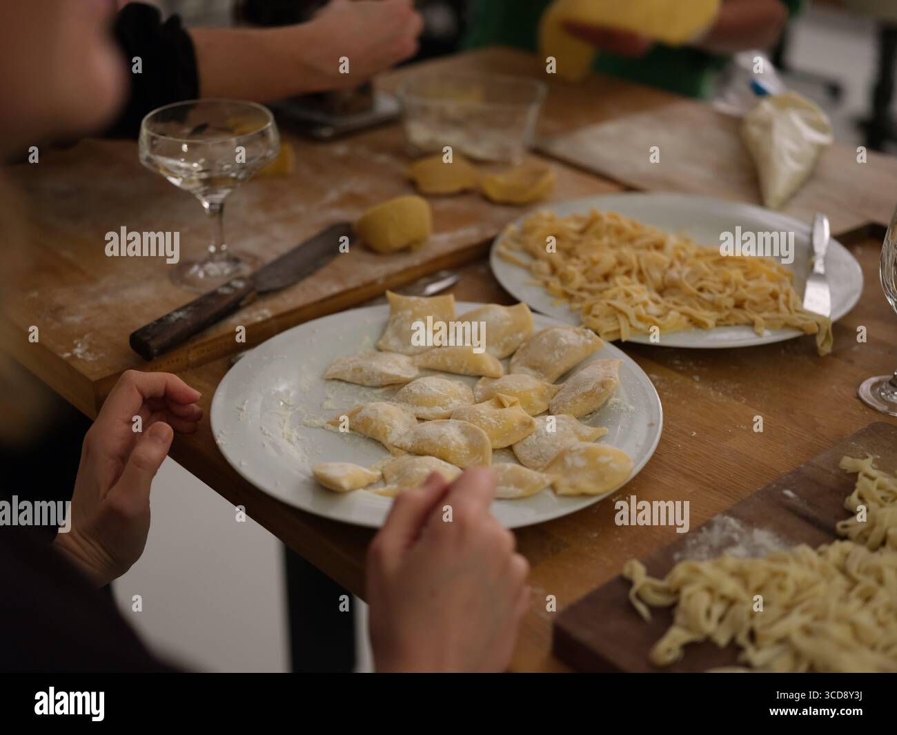 Gruppe von Menschen, die frischen Teig von Hand in der Küche zubereiten, Nahaufnahme des Kochprozesses, kulinarische Kunst und traditionelle Nudelherstellung. Stockfoto