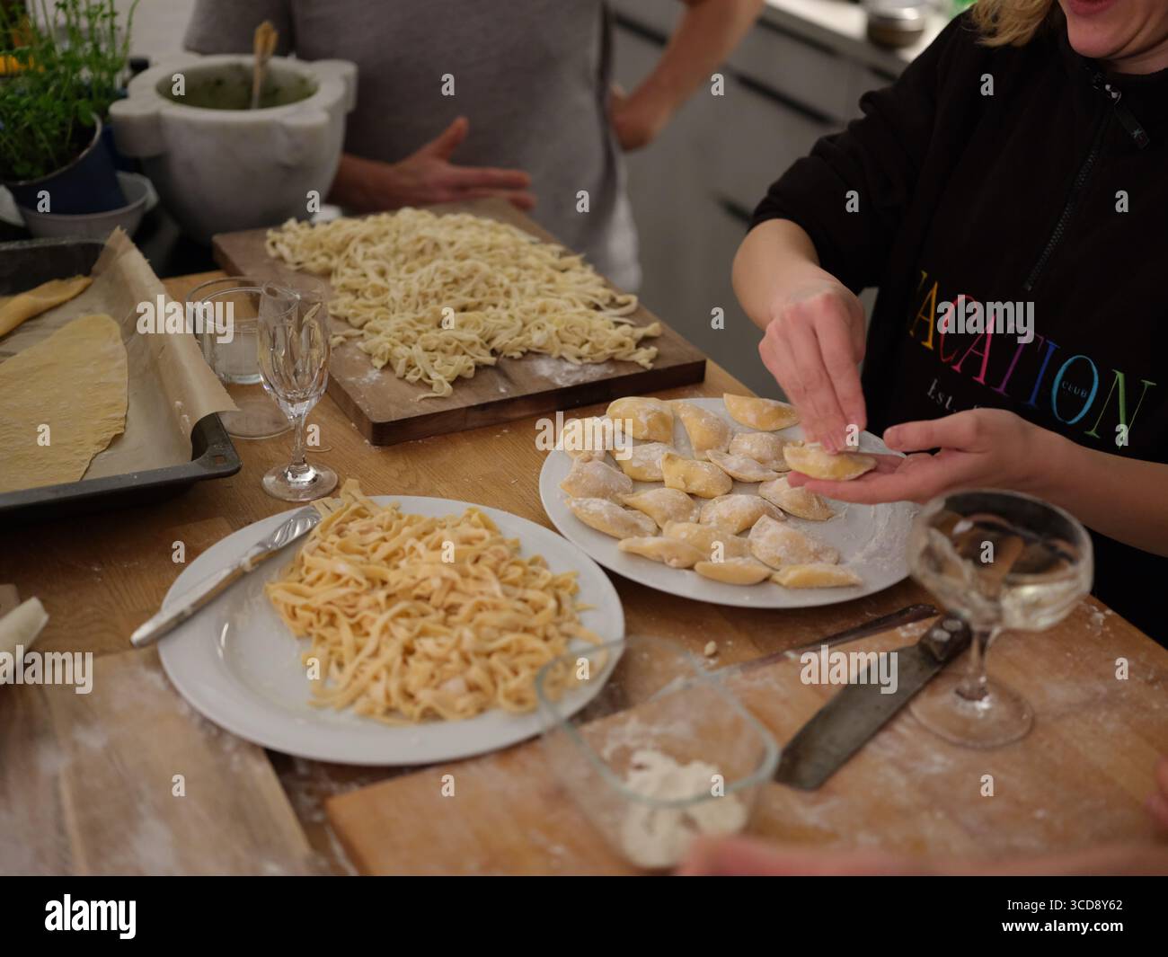 Gruppe von Menschen, die frischen Teig von Hand in der Küche zubereiten, Nahaufnahme des Kochprozesses, kulinarische Kunst und traditionelle Nudelherstellung. Stockfoto