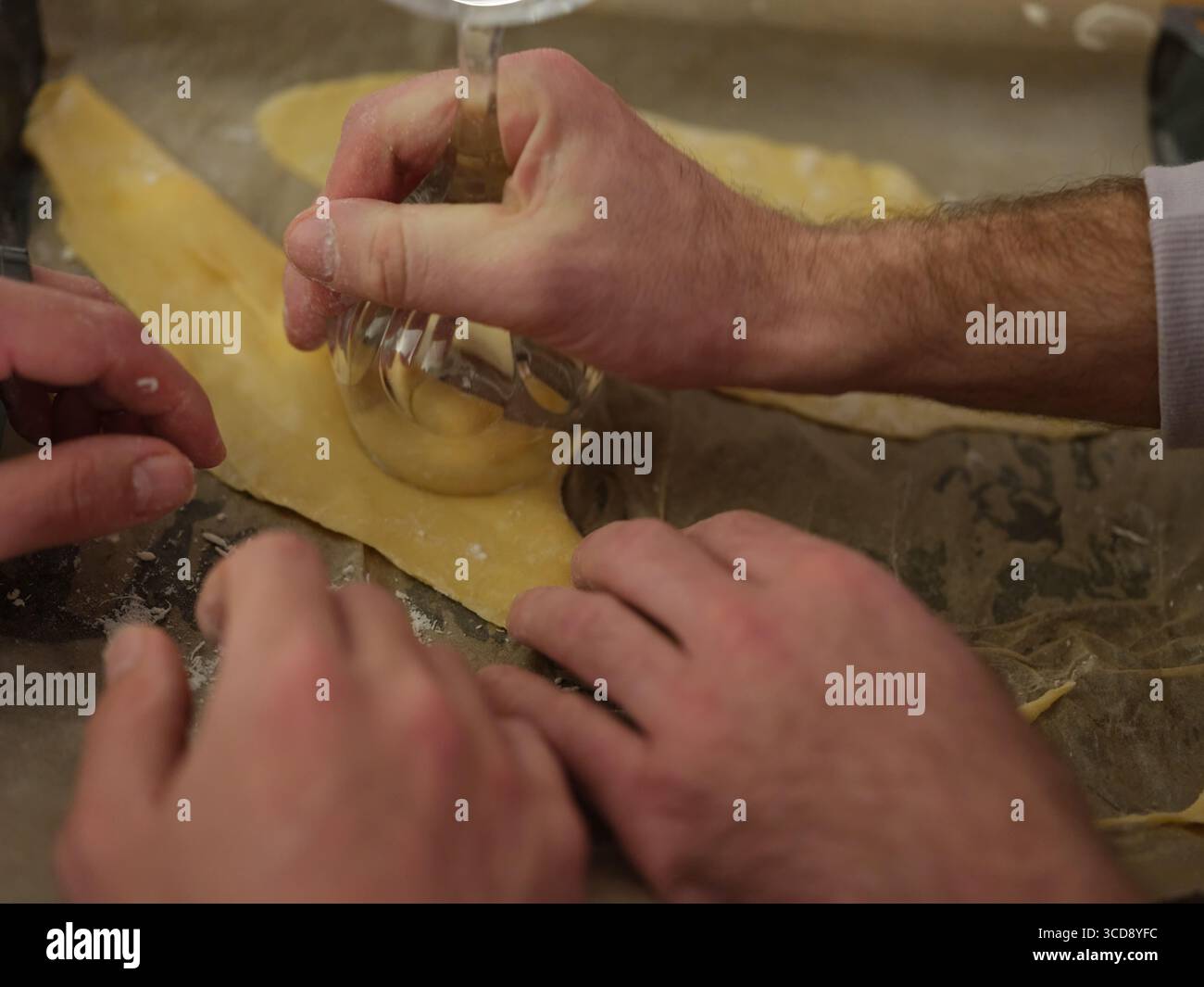 Gruppe von Menschen, die frischen Teig von Hand in der Küche zubereiten, Nahaufnahme des Kochprozesses, kulinarische Kunst und traditionelle Nudelherstellung. Stockfoto