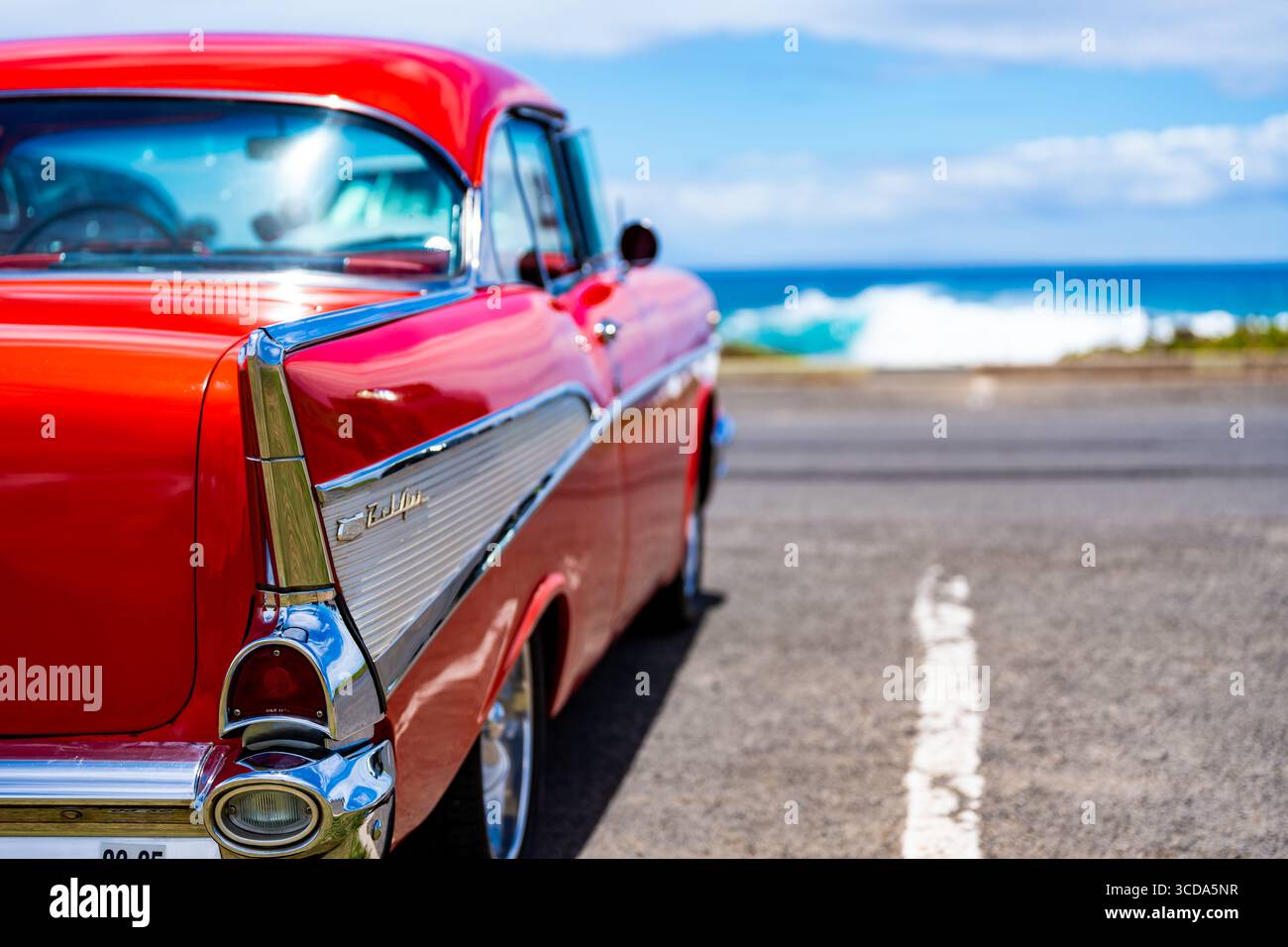 Kräftig rot 1957 Chevy Bel Air parkte im Sonnenlicht und präsentierte sein Chrom und seine Kurven. Eine zeitlose amerikanische Autokultur mit Nostalgie und Vintage Stockfoto