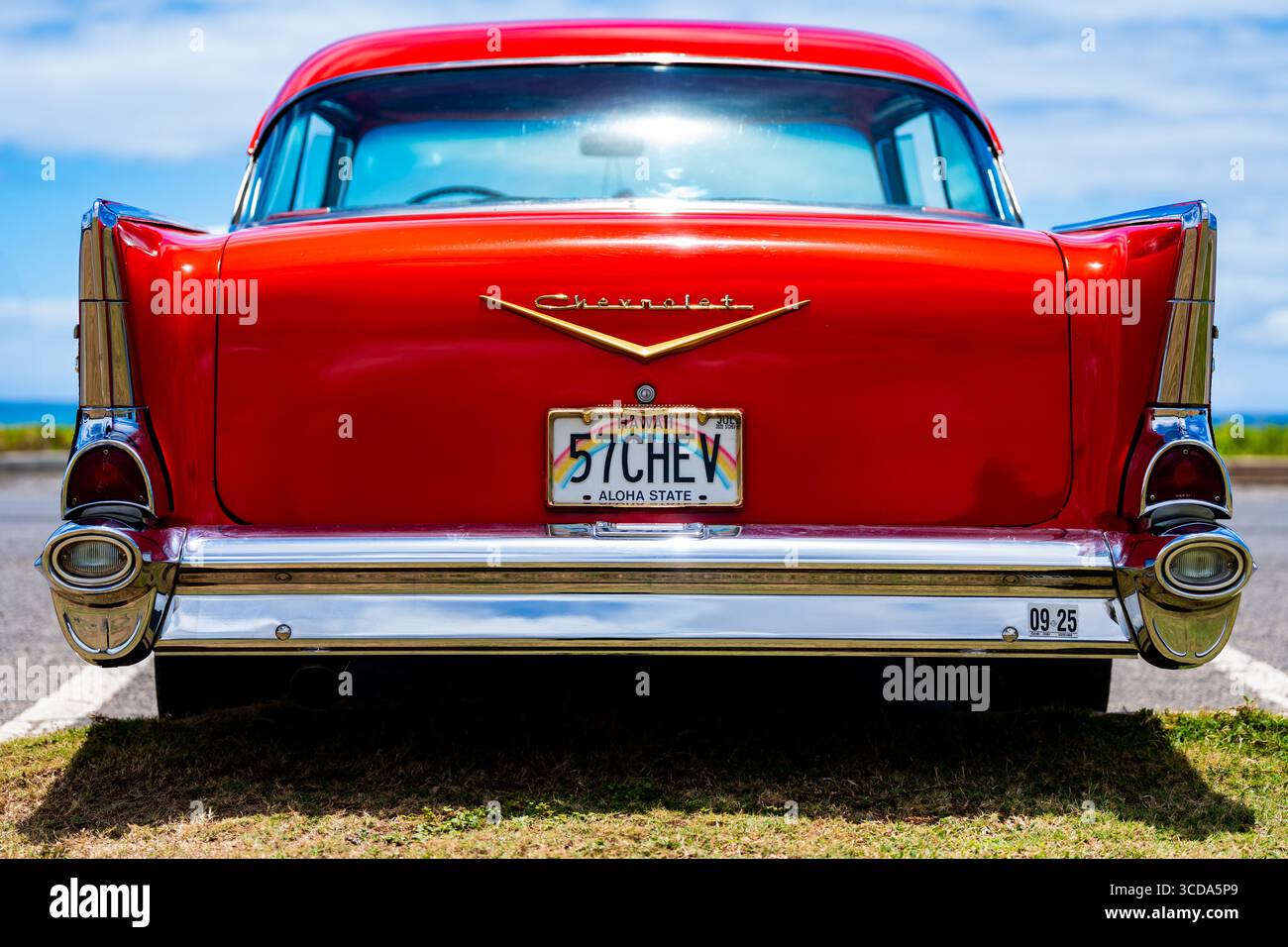 Kräftig rot 1957 Chevy Bel Air parkte im Sonnenlicht und präsentierte sein Chrom und seine Kurven. Eine zeitlose amerikanische Autokultur mit Nostalgie und Vintage Stockfoto