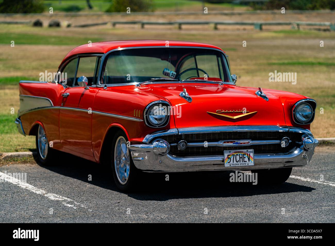 Kräftig rot 1957 Chevy Bel Air parkte im Sonnenlicht und präsentierte sein Chrom und seine Kurven. Eine zeitlose amerikanische Autokultur mit Nostalgie und Vintage Stockfoto