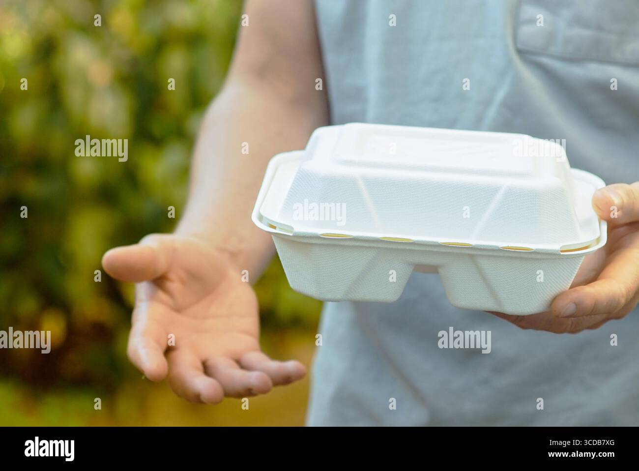Person mit kompostierbarer Lebensmittelbox im Freien. Umweltfreundliche Einwegverpackungen. Nachhaltige Restaurantlieferung und umweltbewusstes Essen Stockfoto