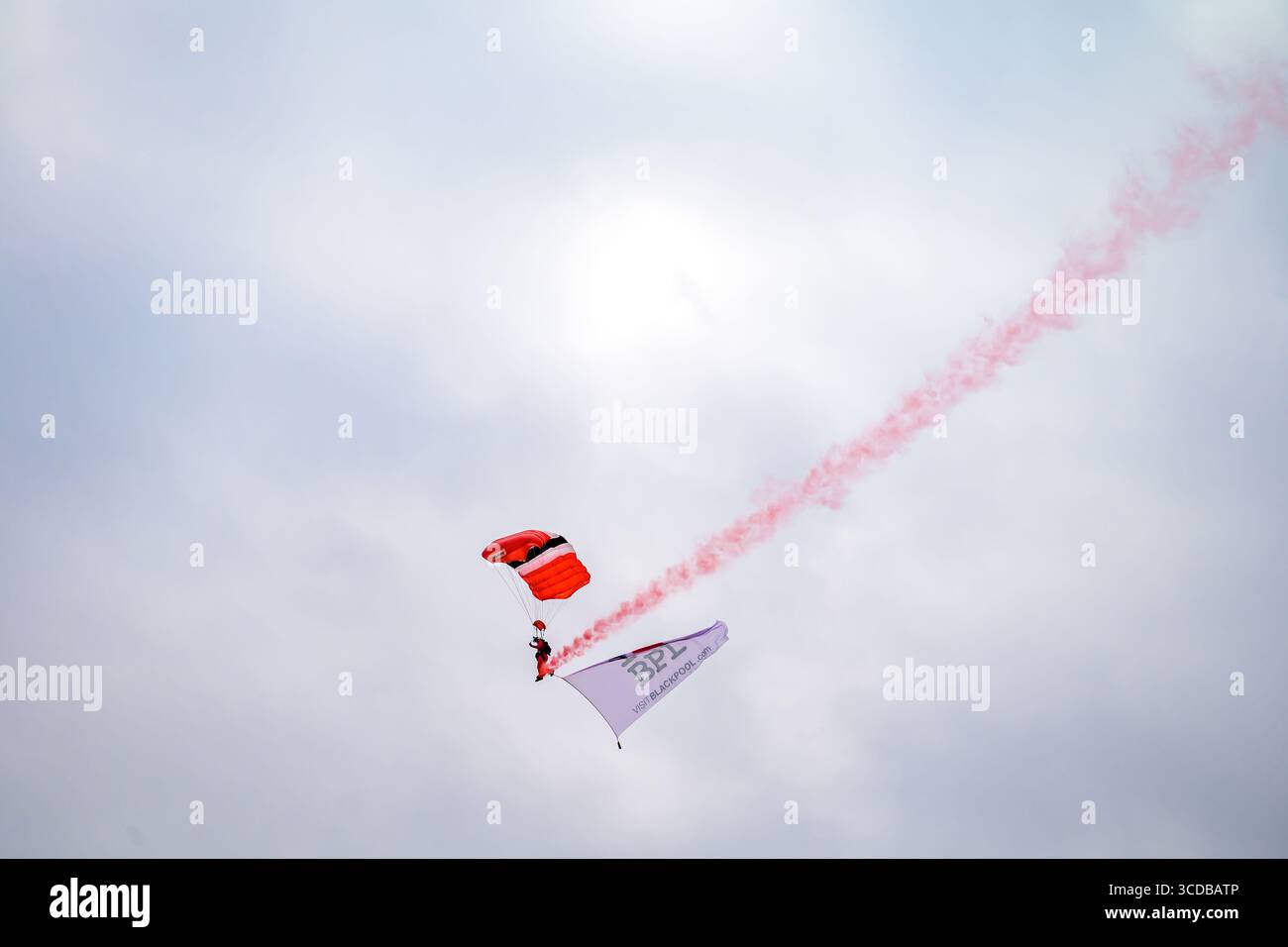 Blackpool, England - 10. August 2025: Ein Mitglied der Red Devils, der Fallschirmspringer des britischen Fallschirmregiments, springt mit einer Flagge auf der Stockfoto