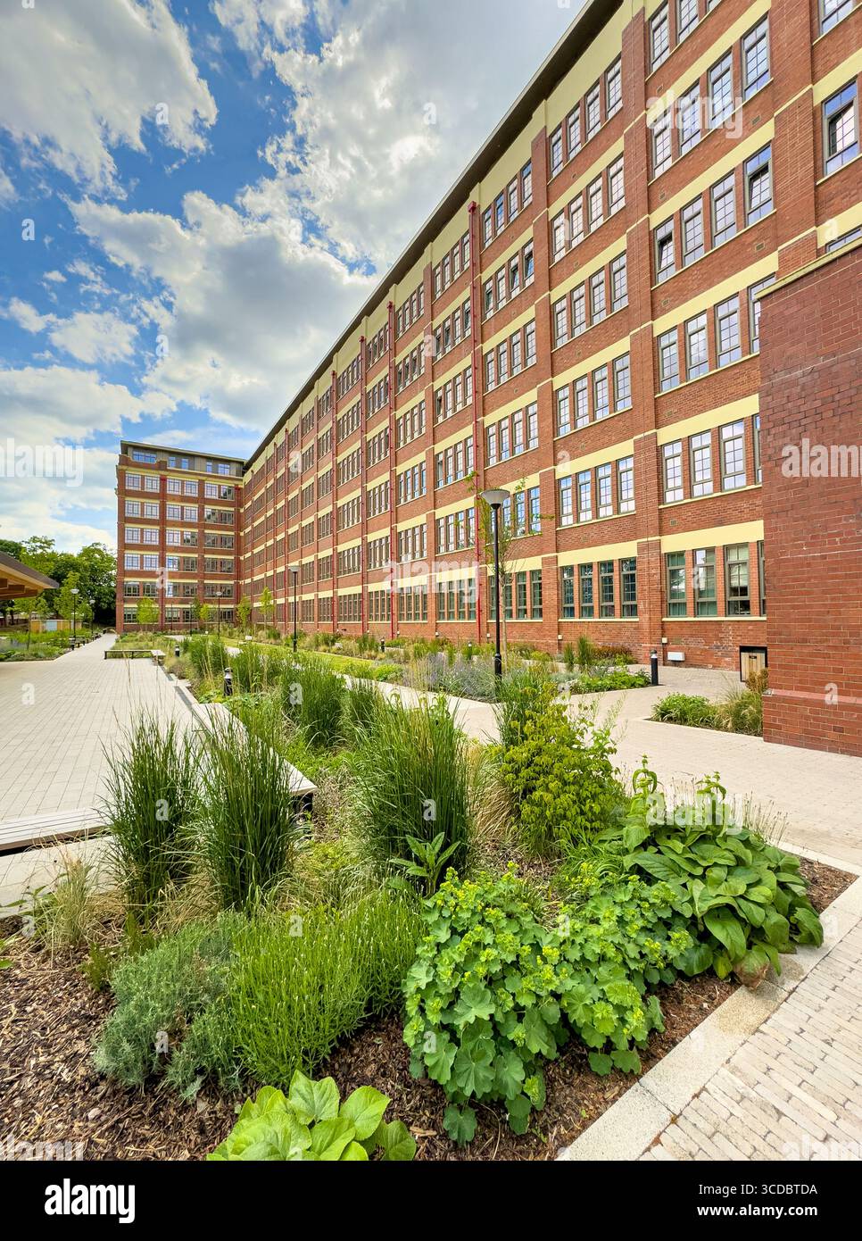 Die Cocoa Works Apartments, eine restaurierte ehemalige Schokoladenfabrik von Rowntree in York, mit rotem Ziegelstein, großen Industriefenstern und einer Landschaftsgestaltung Stockfoto