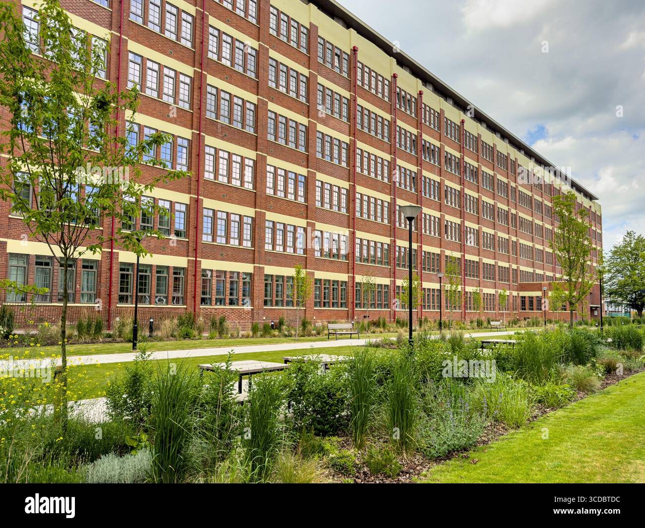 Die Cocoa Works Apartments, eine restaurierte ehemalige Schokoladenfabrik von Rowntree in York, mit rotem Ziegelstein, großen Industriefenstern und einer Landschaftsgestaltung Stockfoto