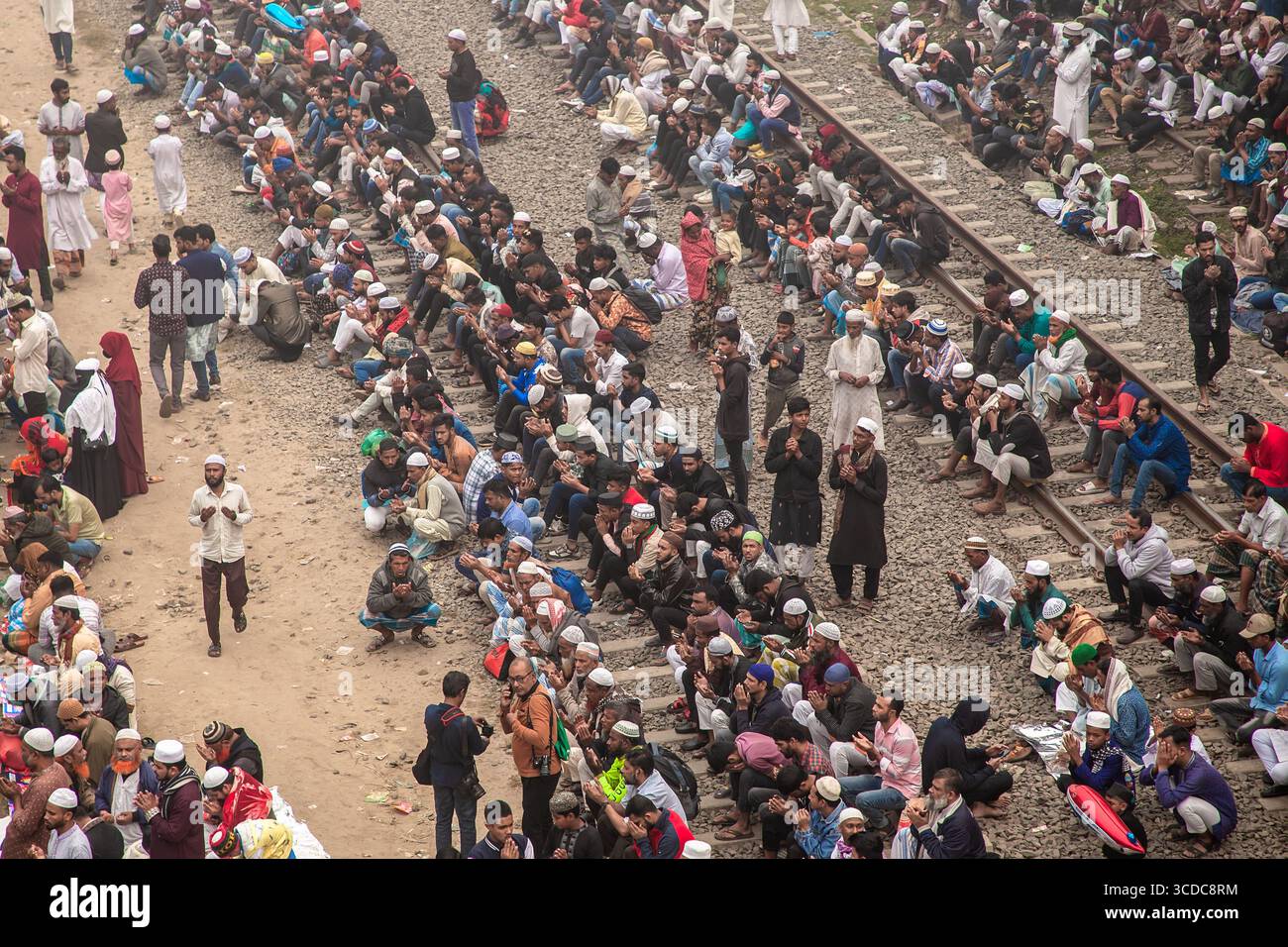 Tongi, Bangladesch - 2. Februar 2025: Aus der Vogelperspektive einer riesigen Versammlung von Menschen, die auf und neben Eisenbahngleisen beten, ein Meer aus weißen Kappen, die sich von den Erdtönen des Bodens abheben. Stockfoto