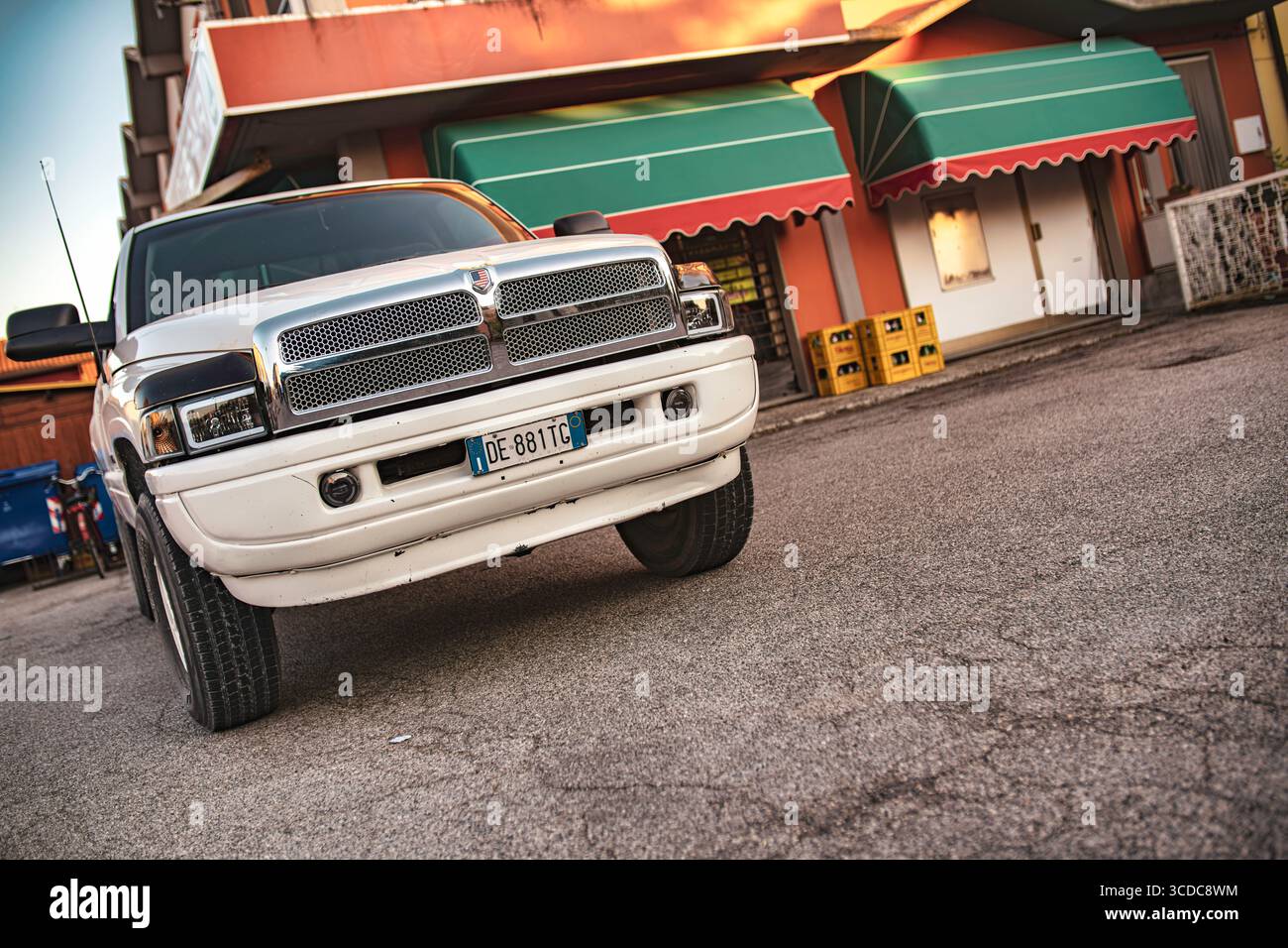 Calaone, italien 13. august 2025: Leistungsstarker weißer Dodge Widder-Pickup-Truck parkt auf Asphalt vor einem Geschäftsgebäude mit grünen und roten Markisen Stockfoto