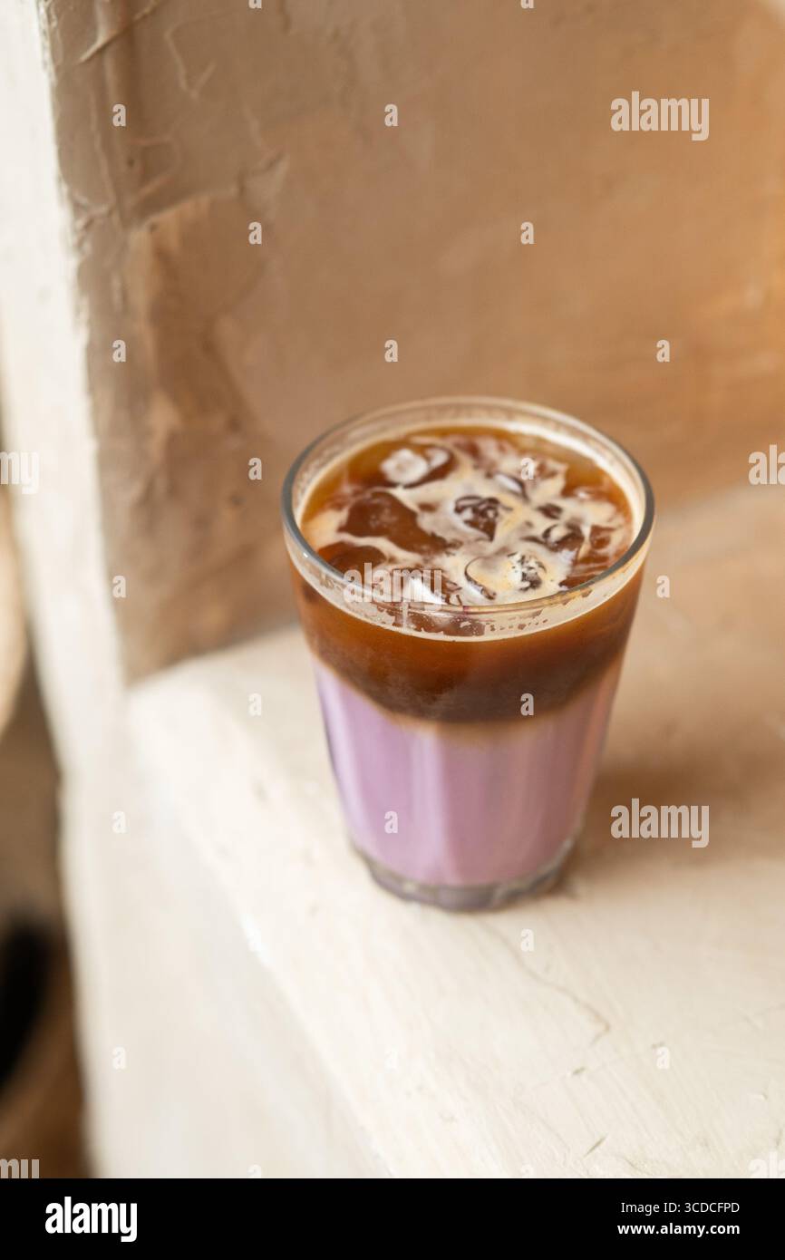 Ein erfrischendes Glas Lavendelkaffee in minimalistischer Atmosphäre. Kalte Brauerei mit blumigem Aroma, weichen Pastelltönen, gemütlich und modern. Stockfoto