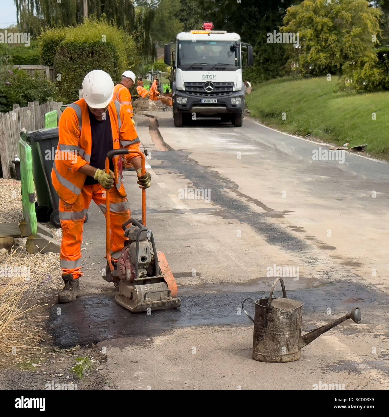 Winchester Hampshire England Vereinigtes Königreich. 07.08.2025. Arbeiter verwenden einen Verdichter, um die Asphaltverlegung nach der Installation eines neuen Glasfasernetzes in einem V Stockfoto