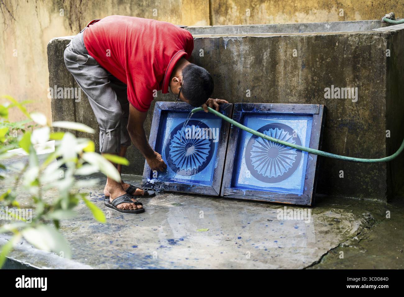 Mitarbeiter des Assam Khadi and Village Industries Board, der den Siebdruckblock Ashoka Stambh in einer Produktionseinheit der indischen Nationalflagge reinigt Stockfoto