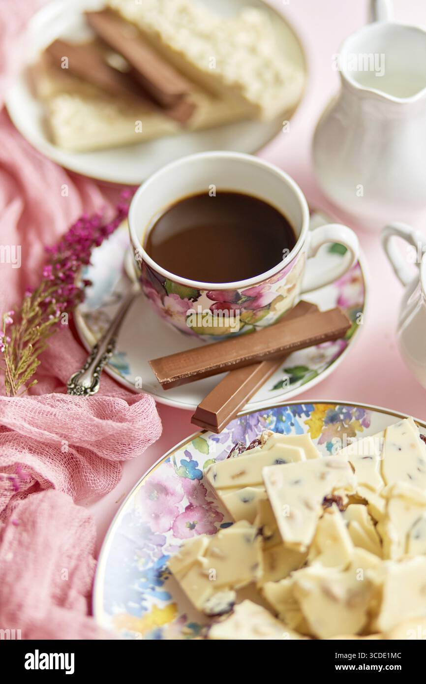Köstliches Dessert auf rosa Hintergrund. Heißer Kaffee oder dunkle Schokolade mit weißer Schokolade und Schokoriegel. Flache Lage, Seitenansicht Stockfoto