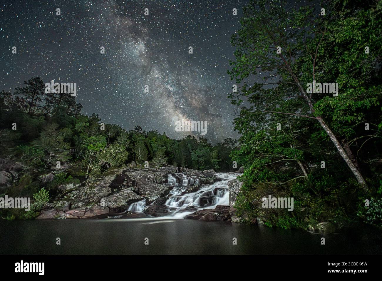 Die Milchstraße erstreckt sich über den Nachthimmel über den Rocky Falls bei Eminence, Missouri, während das kaskadierende Wasser sanft unter den Sternen leuchtet – ein ruhiges B Stockfoto