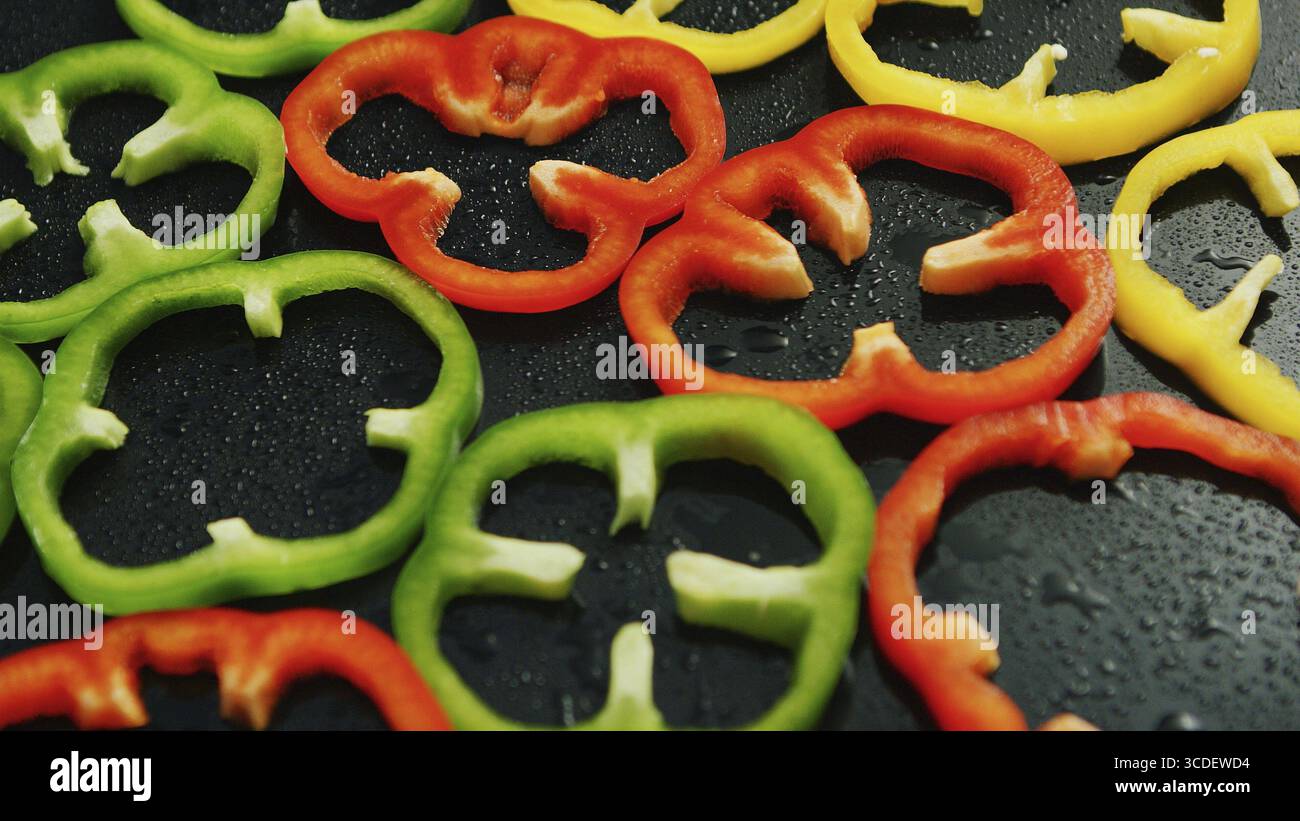 Nahaufnahme des bestehend Schicht von bunten Ringe geschnitten Paprika auf nasser Oberfläche Stockfoto