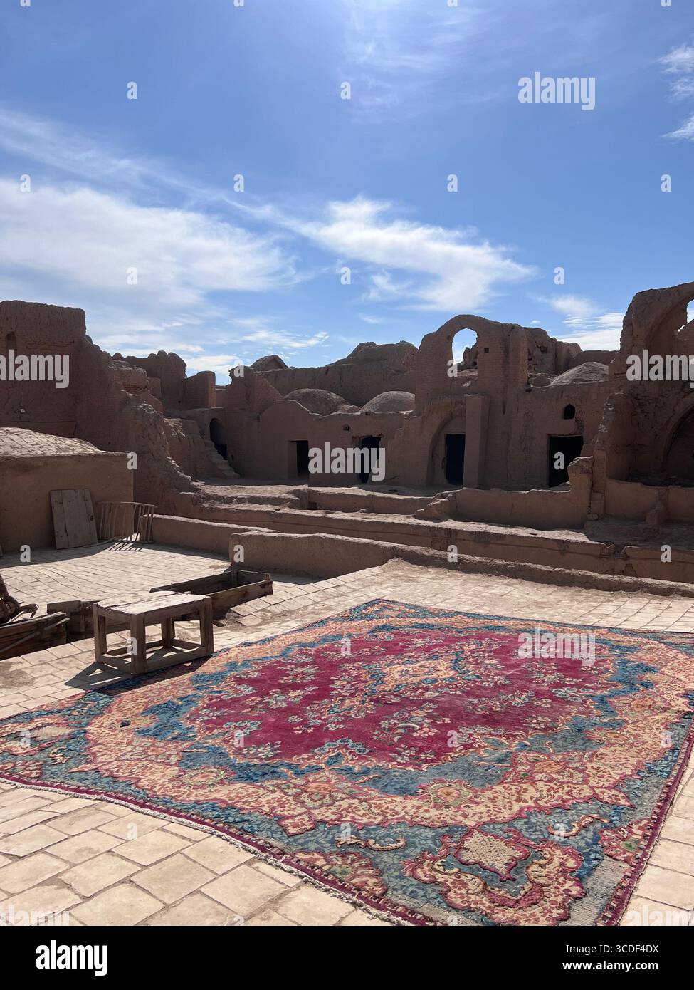 Ein lebhafter persischer Teppich, der sich über den Innenhof der Festung SAR Yazd erstreckt und Tradition mit alten lehmwänden verbindet. Stockfoto Ein lebhafter persischer Teppich, der sich über den Innenhof der Festung SAR Yazd erstreckt und Tradition mit alten lehmwänden verbindet. Stockfoto
