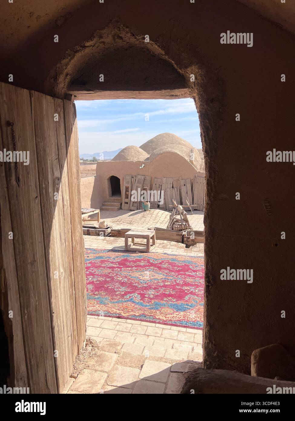 Blick vom Inneren der Festung SAR Yazd, Blick durch eine alte hölzerne Tür auf den Innenhof und die Kuppelbauten. Stockfoto Blick vom Inneren der Festung SAR Yazd, Blick durch eine alte hölzerne Tür auf den Innenhof und die Kuppelbauten. Stockfoto