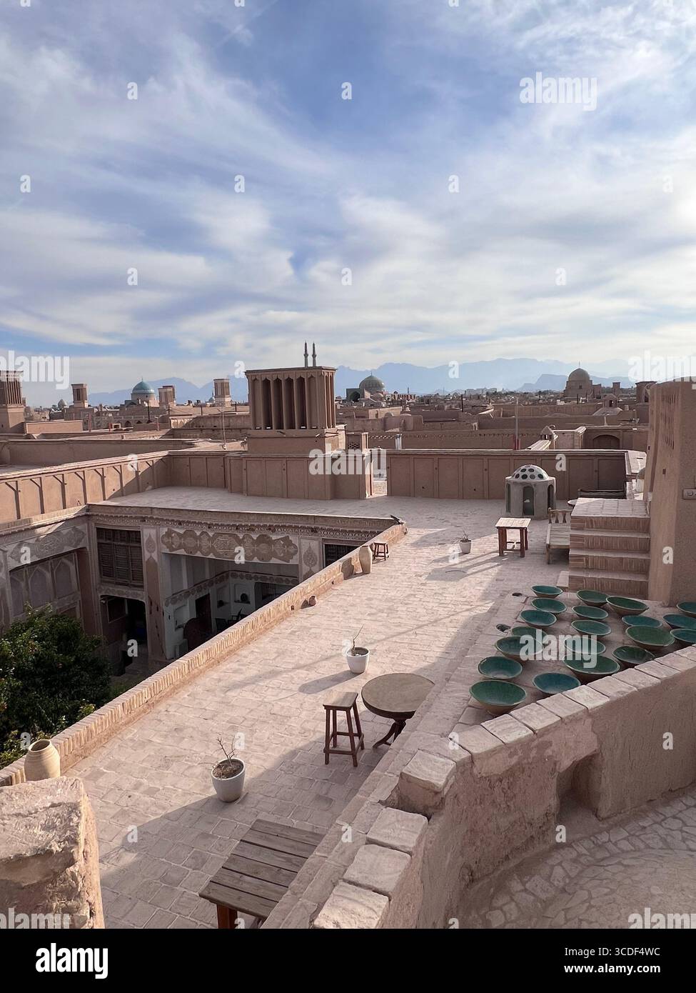 Großer Blick von der Dachterrasse auf das Honar Café, Yazd, mit Windfängern, Bergen und der historischen Architektur der Stadt. Stockfoto Großer Blick von der Dachterrasse auf das Honar Café, Yazd, mit Windfängern, Bergen und der historischen Architektur der Stadt. Stockfoto
