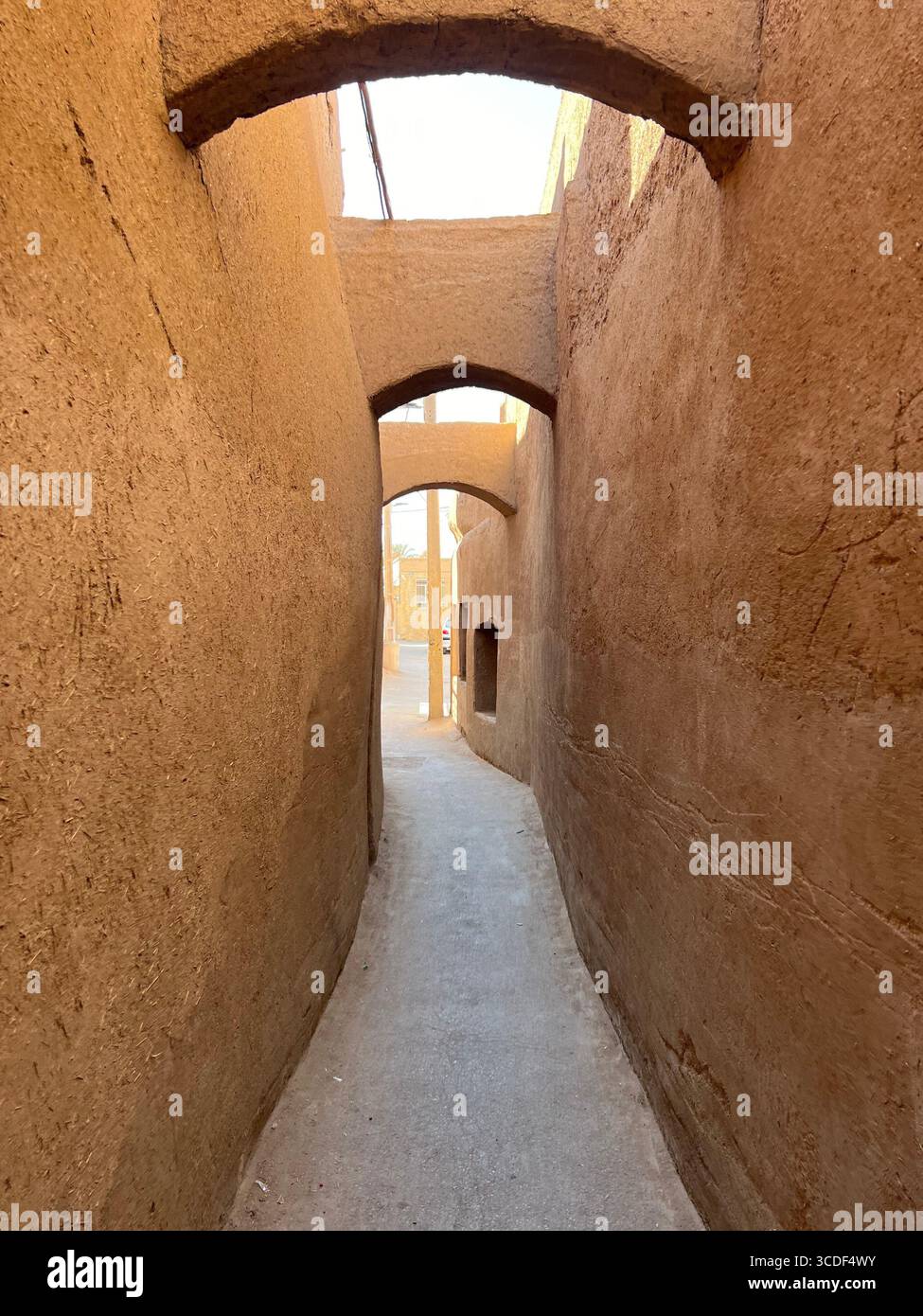 Enge lehmgasse mit traditionellen Bögen in Yazd, Iran, spiegelt den Charme der persischen Wüstenarchitektur wider. Stockfoto Enge lehmgasse mit traditionellen Bögen in Yazd, Iran, spiegelt den Charme der persischen Wüstenarchitektur wider. Stockfoto
