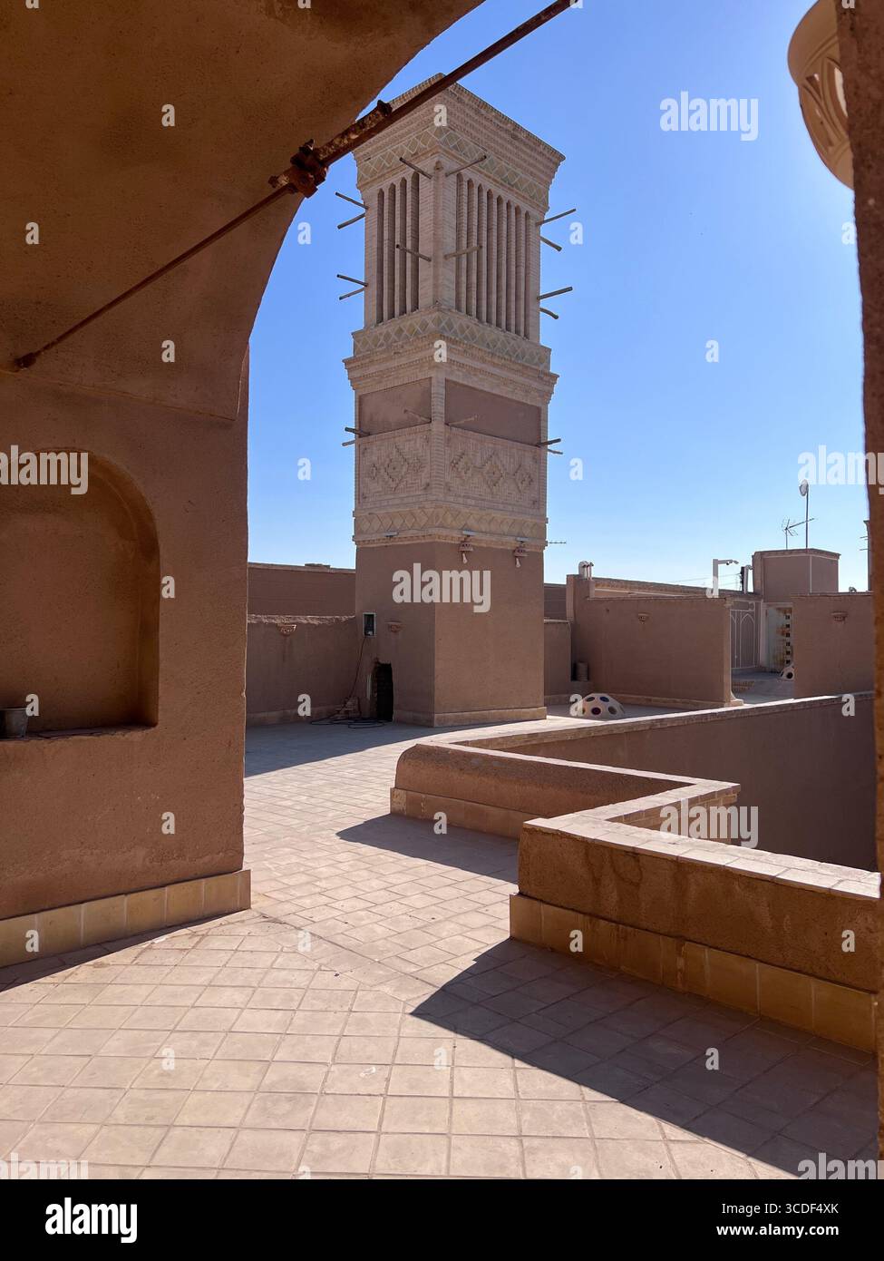 Ein kunstvoller Windfänger, eingerahmt von lehmwänden in Yazd, Iran, der das komplexe persische Design und das Erbe der Wüste zeigt. Stockfoto Ein kunstvoller Windfänger, eingerahmt von lehmwänden in Yazd, Iran, der das komplexe persische Design und das Erbe der Wüste zeigt. Stockfoto