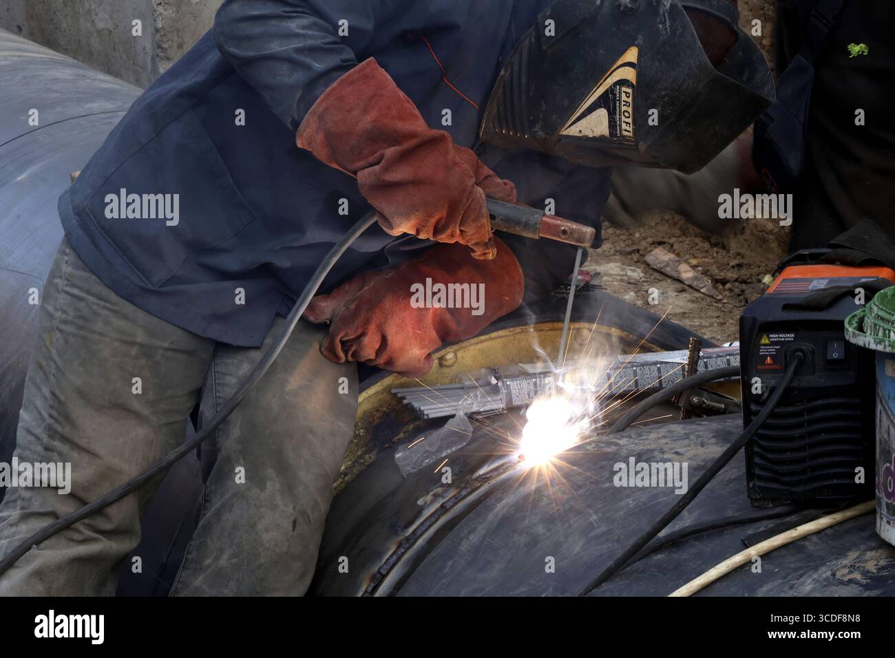 Nicht exklusiv: Ein Arbeiter schweißt zwei isolierte Rohre bei größeren Reparaturen an einem der Fernwärmesysteme der Stadt, Charkiv, Ukraine, auf Au Stockfoto