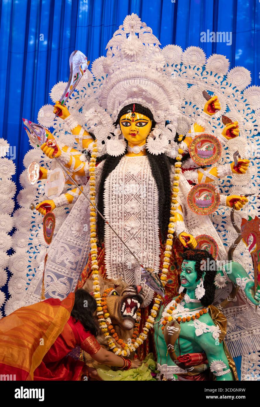 Statue der Göttin durga mit Anbeterin, die während der Abenddämmerung bei Tageslicht betet Stockfoto