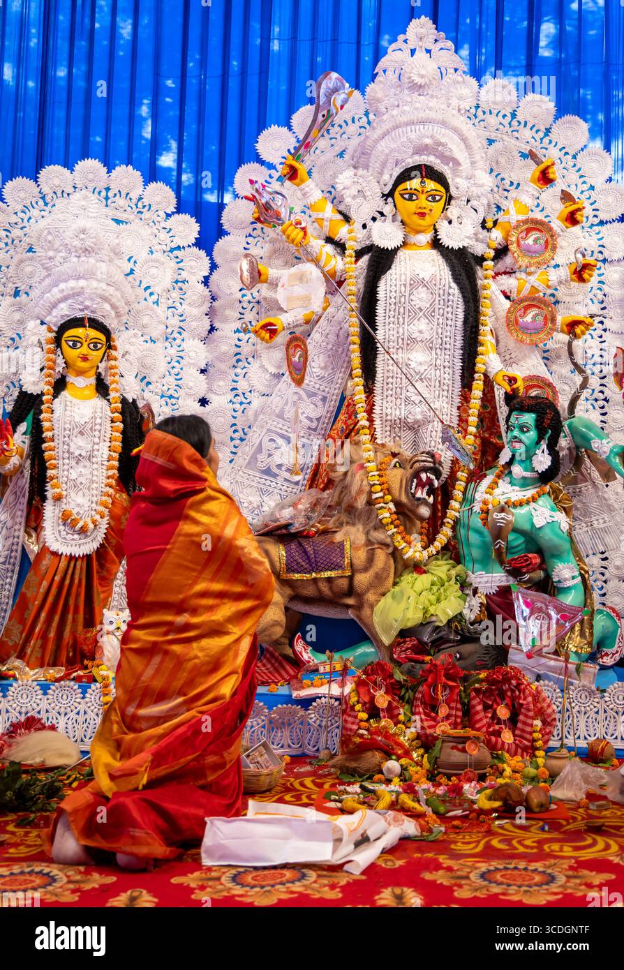 Statue der Göttin durga mit Anbeterin, die während der Abenddämmerung bei Tageslicht betet Stockfoto