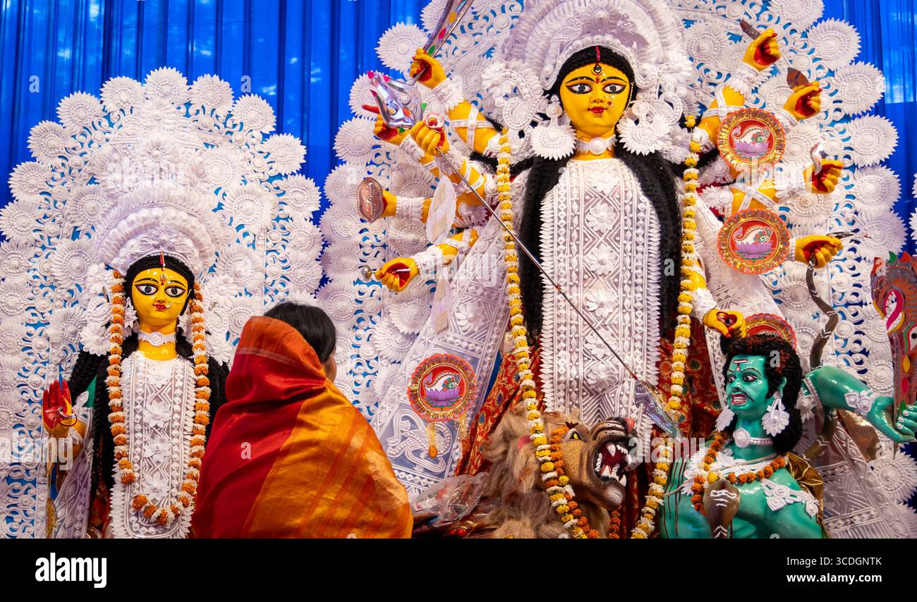 Statue der Göttin durga mit Anbeterin, die während der Abenddämmerung bei Tageslicht betet Stockfoto