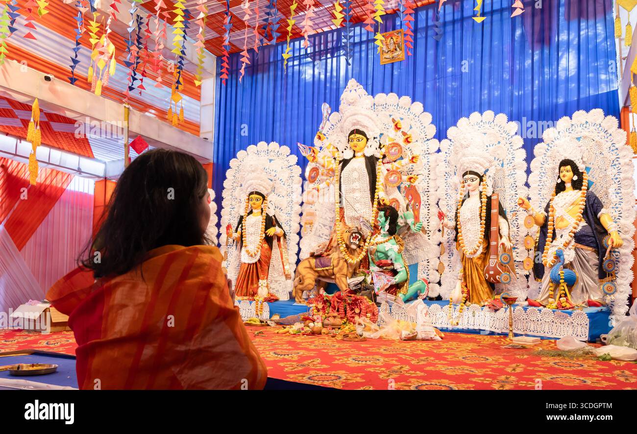 Statue der Göttin durga mit Anbeterin, die während der Abenddämmerung bei Tageslicht betet Stockfoto